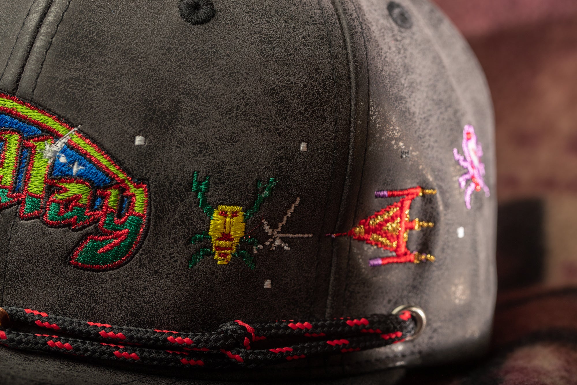 a close-up view of a black baseball cap with colorful embroidered designs on the front.