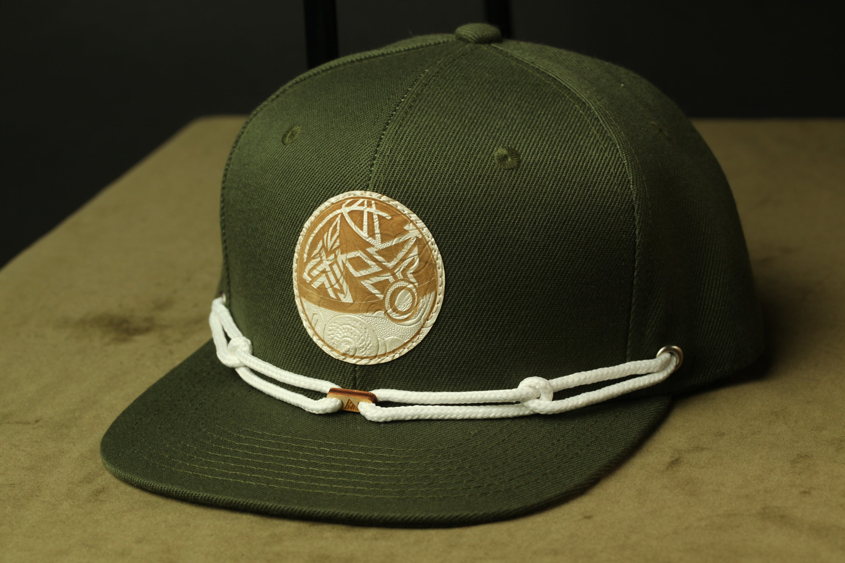 A green baseball cap with a white circular patch on the front, featuring a design or logo.