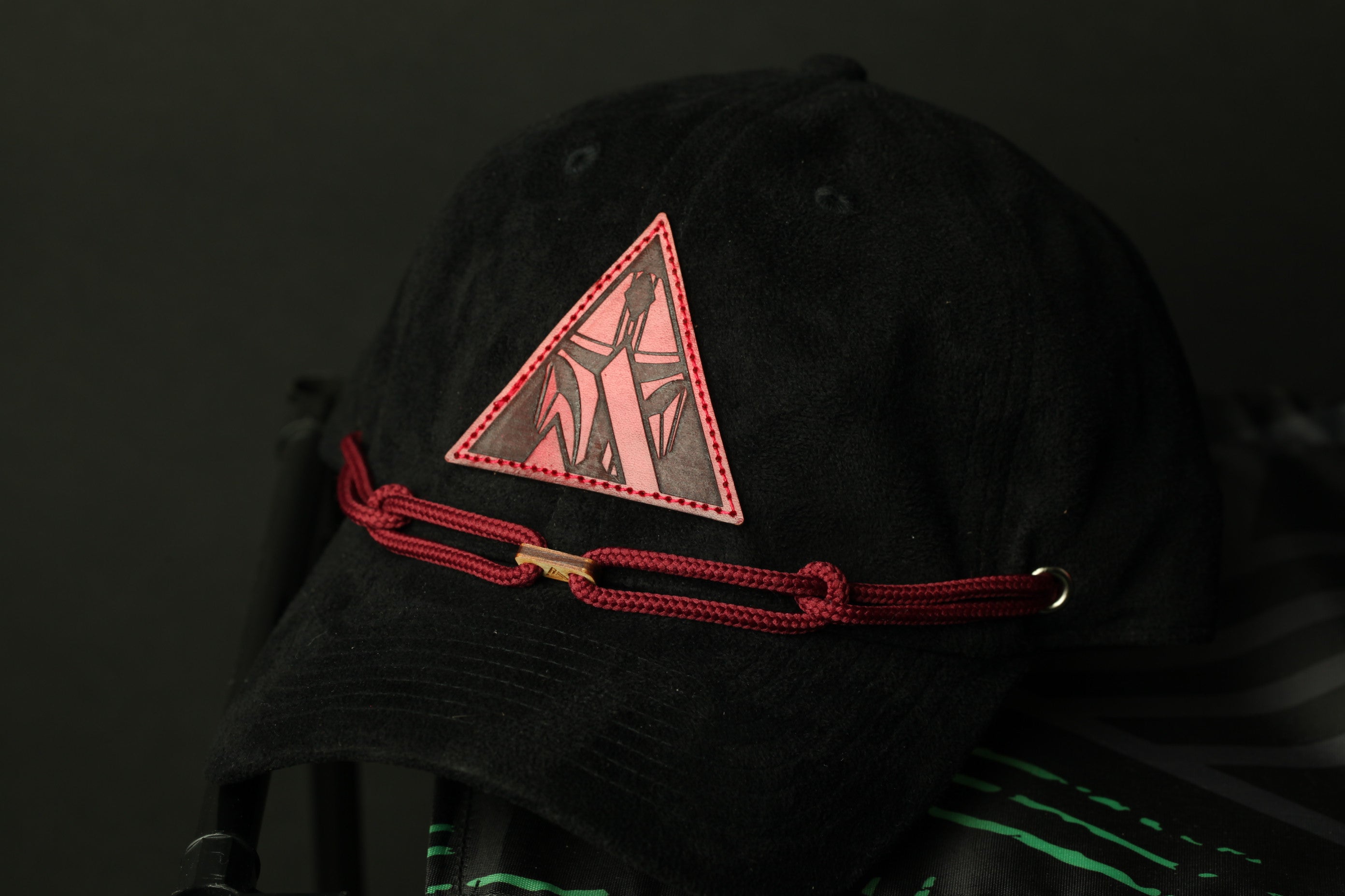 A black baseball cap with a red triangular patch on the front.