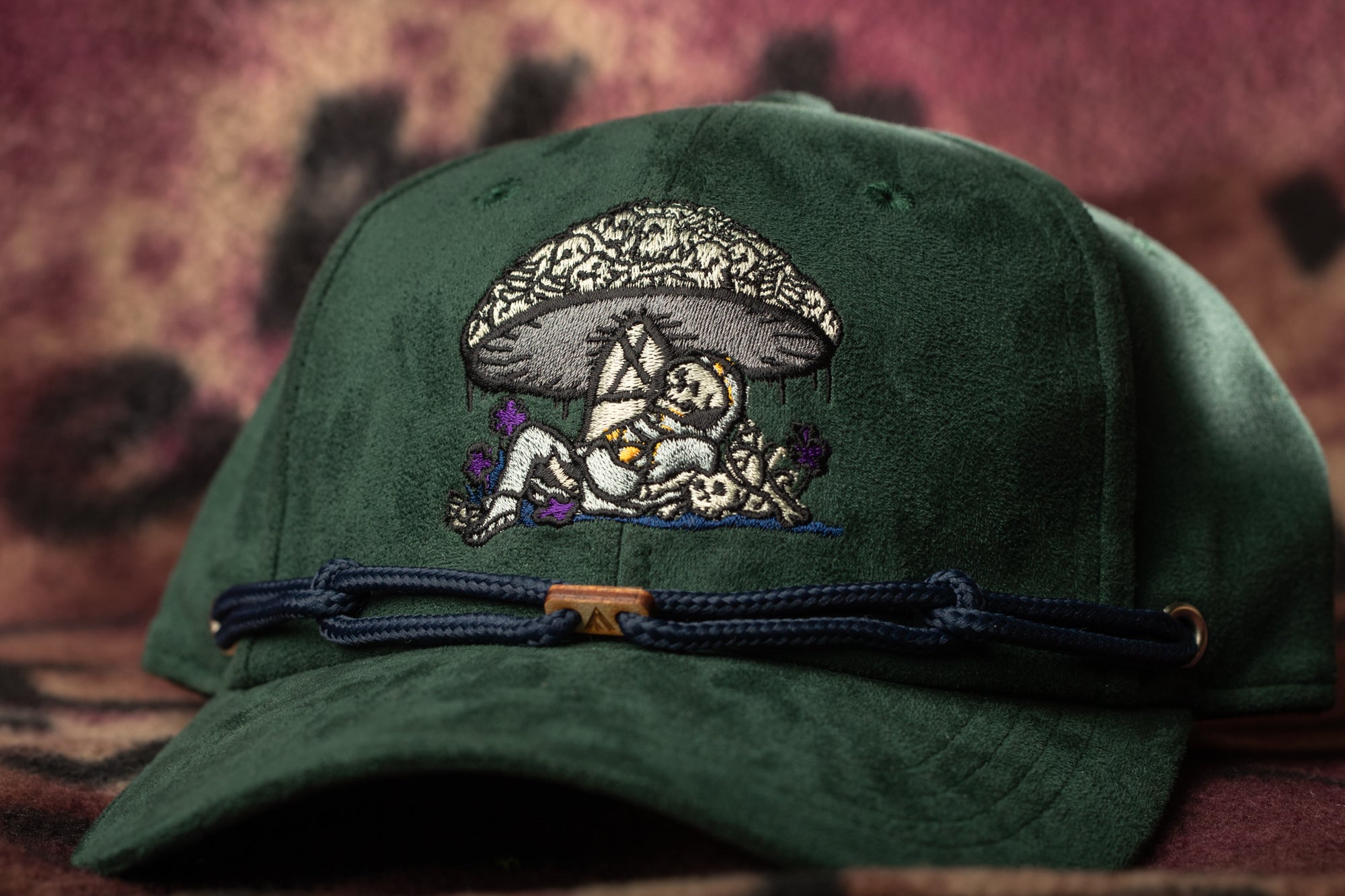 A green baseball cap with a detailed embroidered design on the front.
