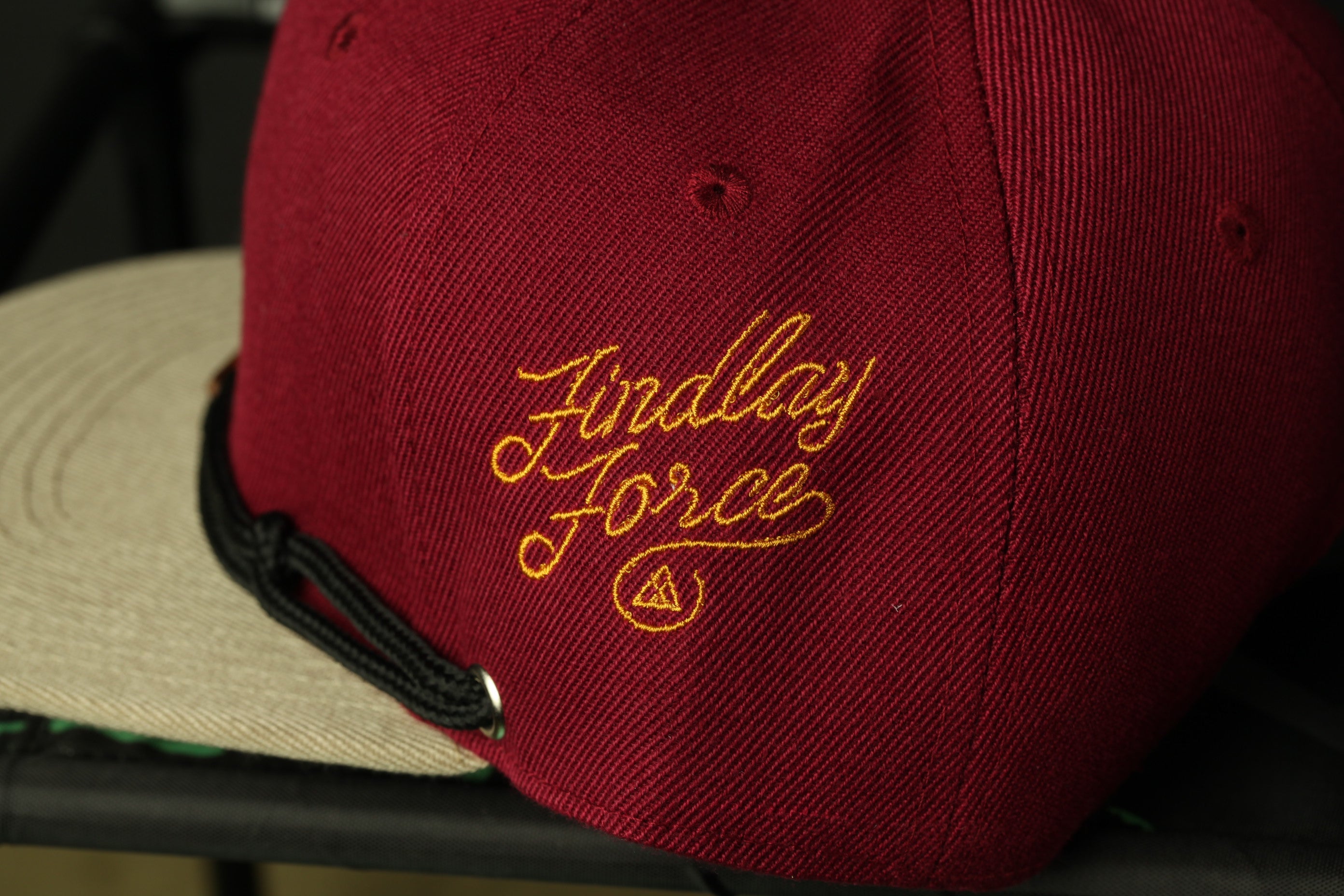 A close-up view of a maroon baseball cap with the embroidered text "Findlay Force" on it.