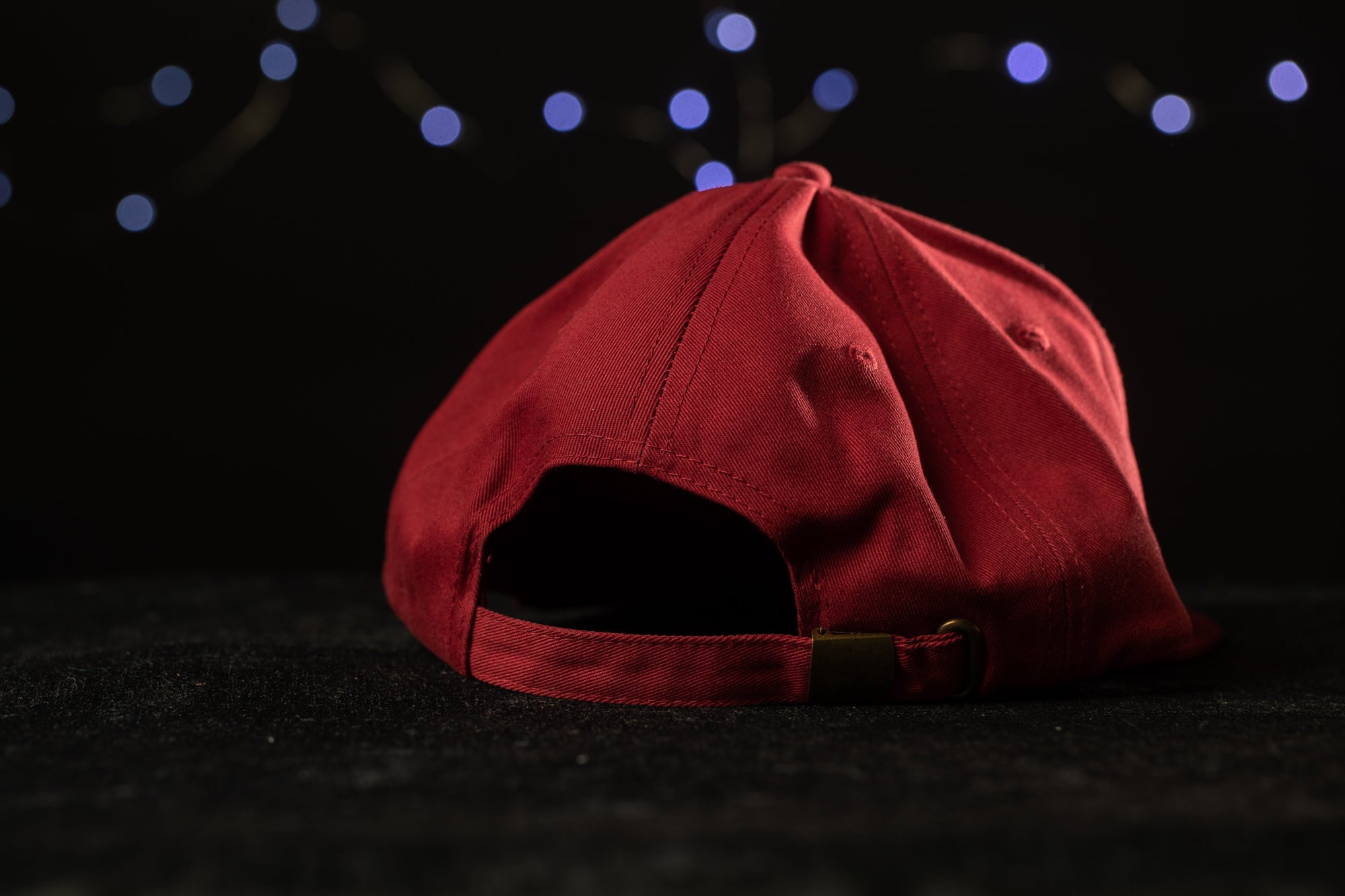 A red baseball cap is shown against a dark background with blue lights in the background.