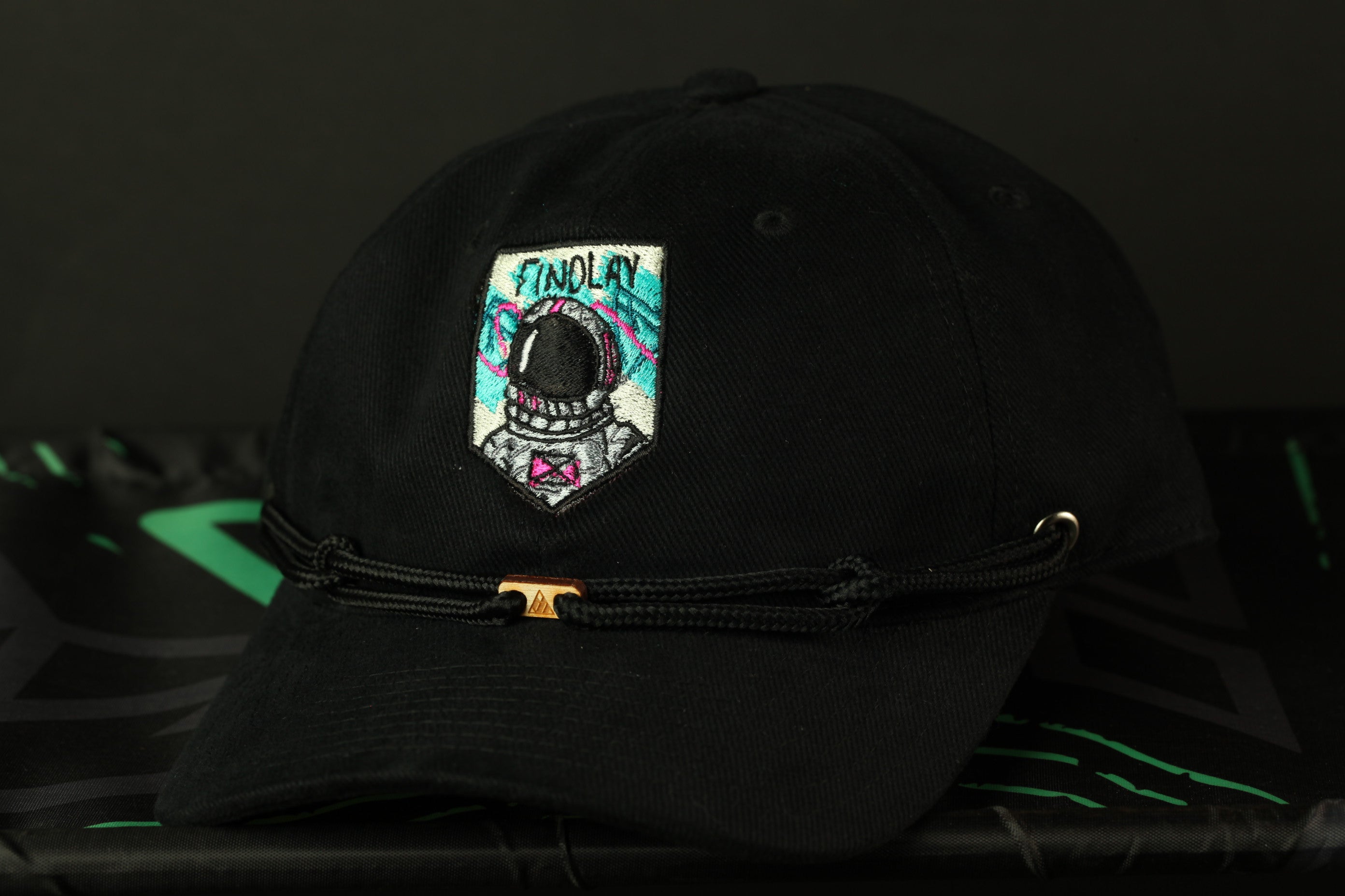 A black baseball cap with a colorful patch on the front, featuring an astronaut helmet and the word "FINDOLAY" written on it.