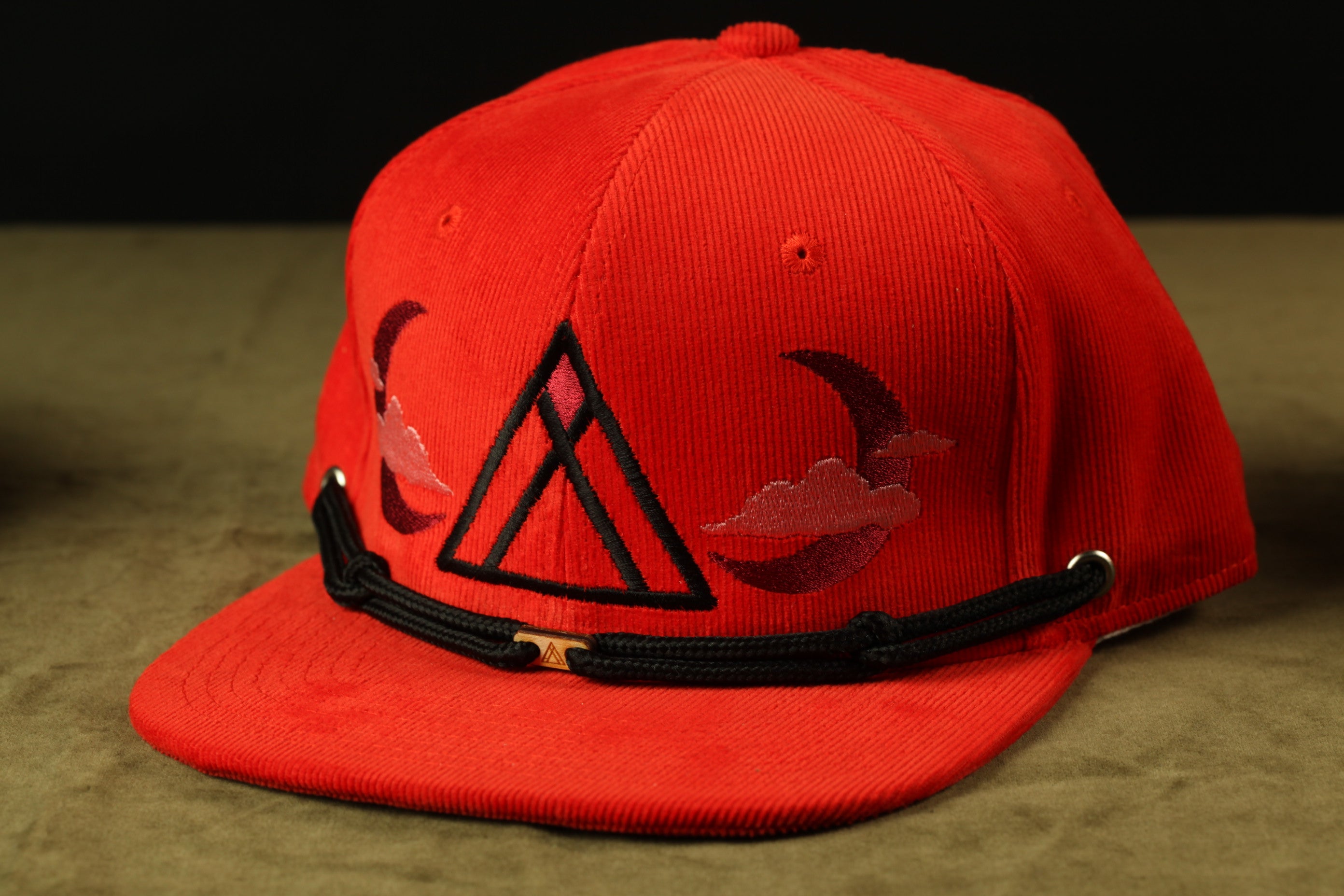 A red baseball cap with a black brim and a triangular logo on the front.
