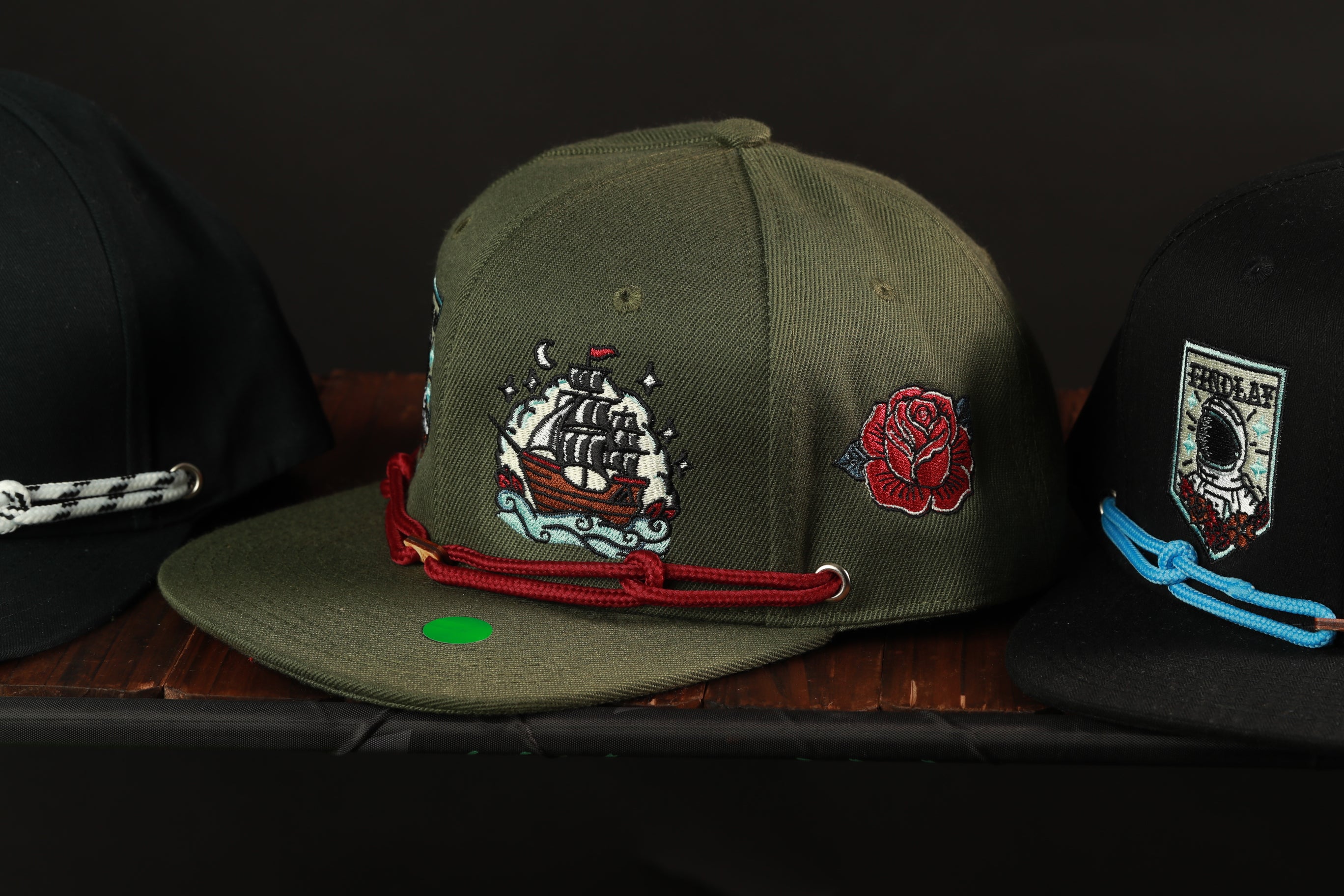 Three baseball caps with different designs and colors are displayed on a wooden surface.