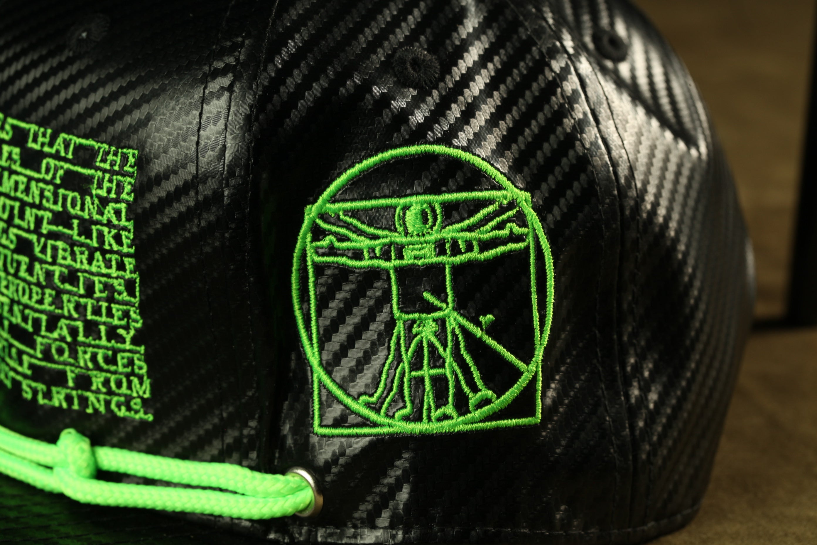 a close-up view of a black baseball cap with a green embroidered logo on the front.