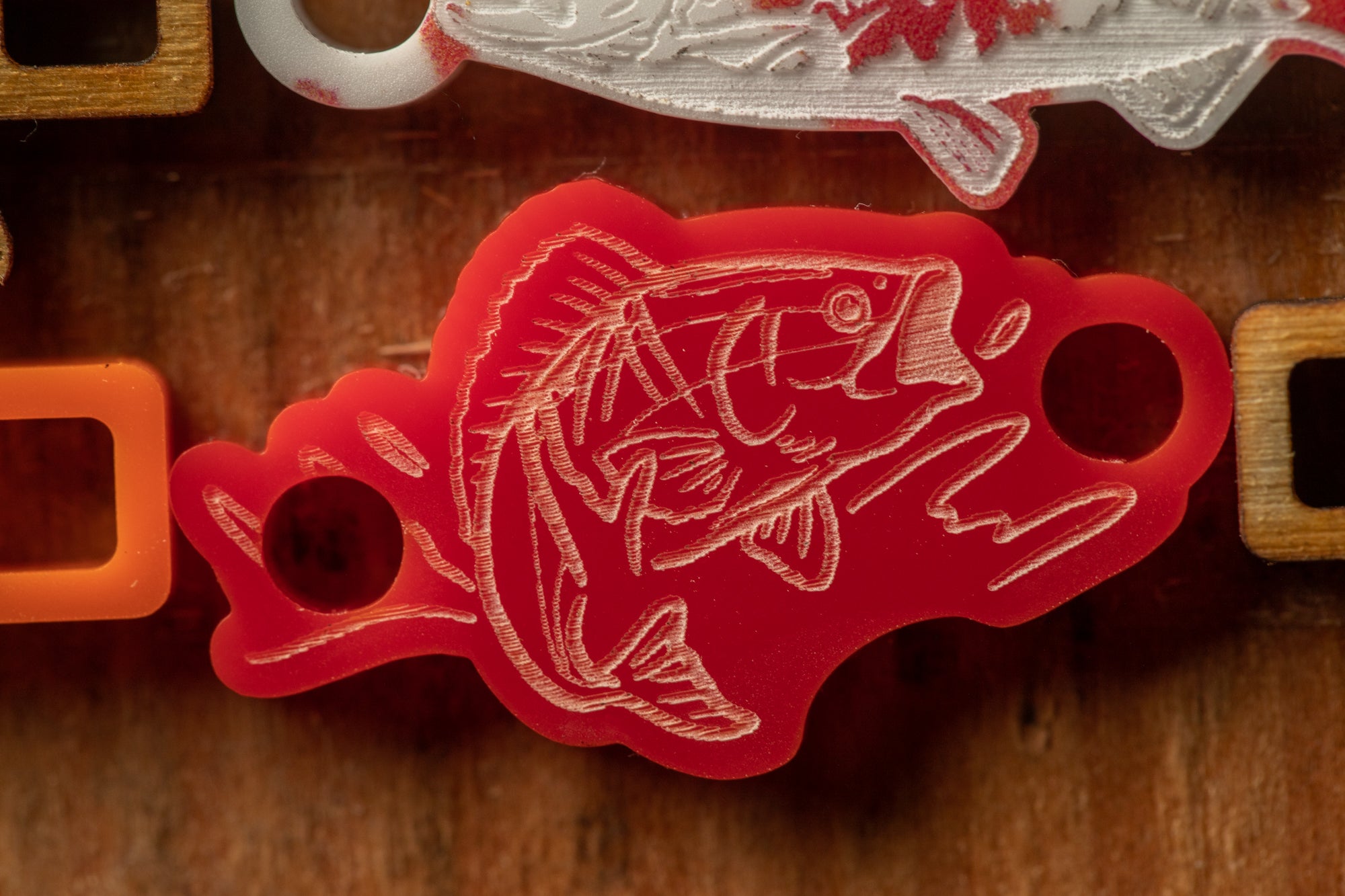 a close-up view of a red plastic object with a fish design on it, placed on a wooden surface.
