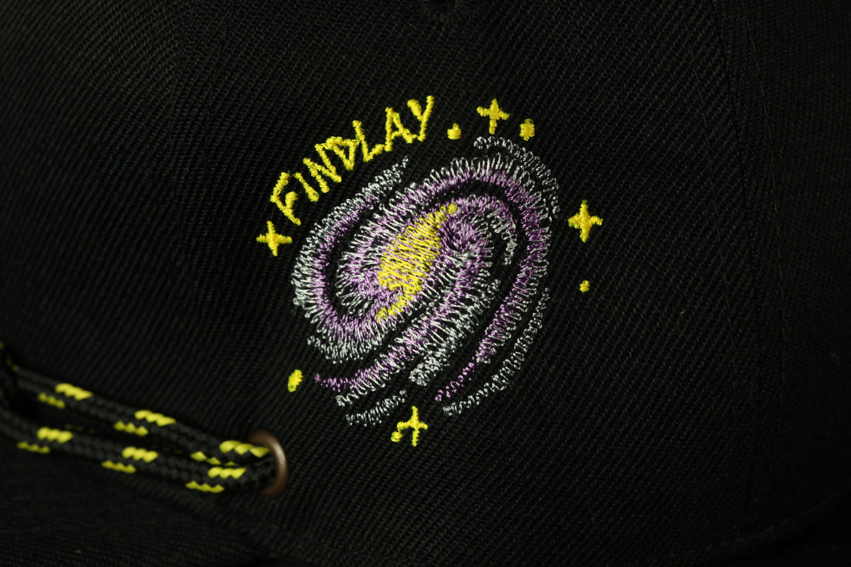 a close-up view of a black baseball cap with a colorful embroidered design on the front.