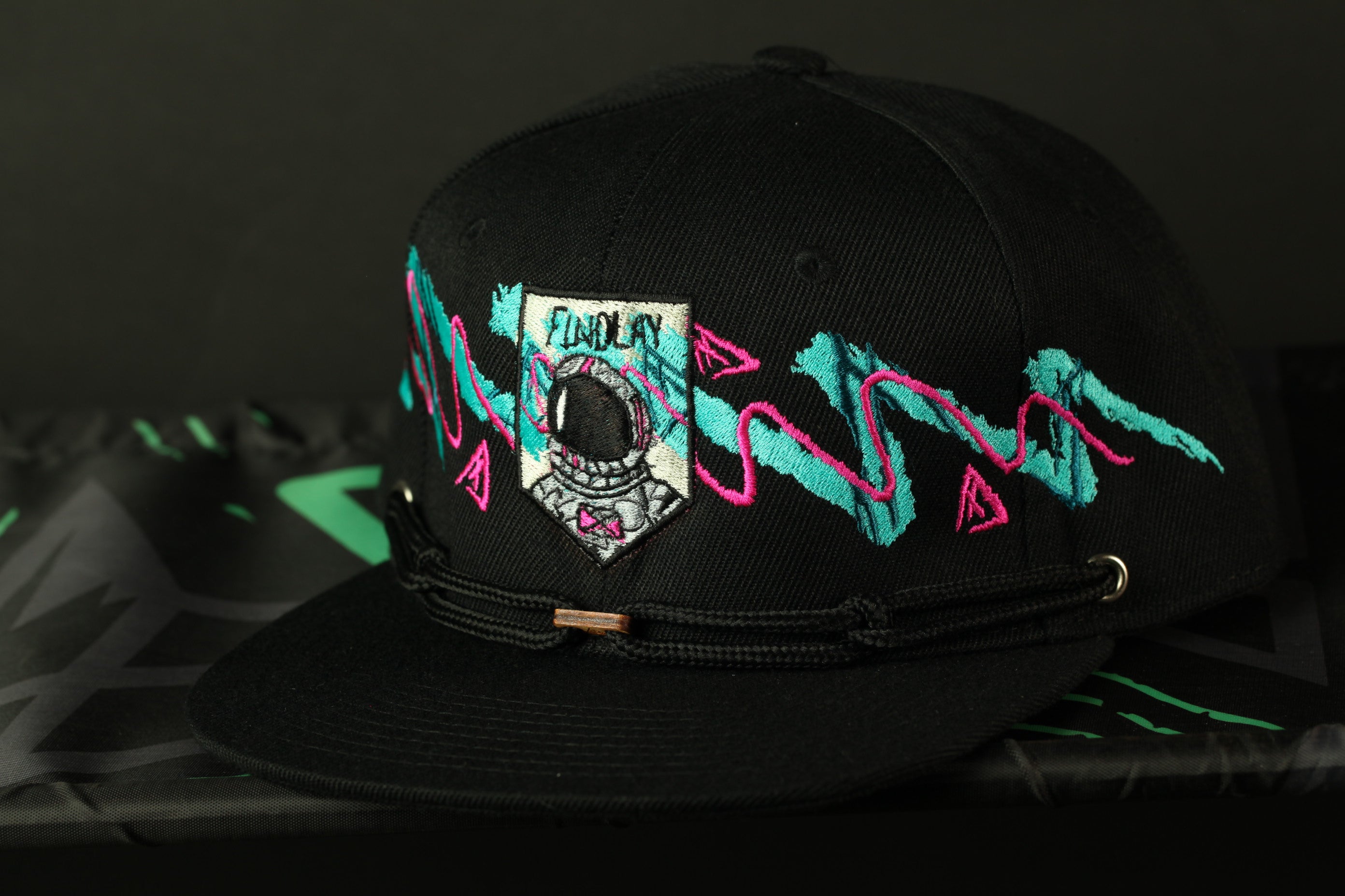 A black baseball cap with colorful, abstract designs and text on it.
