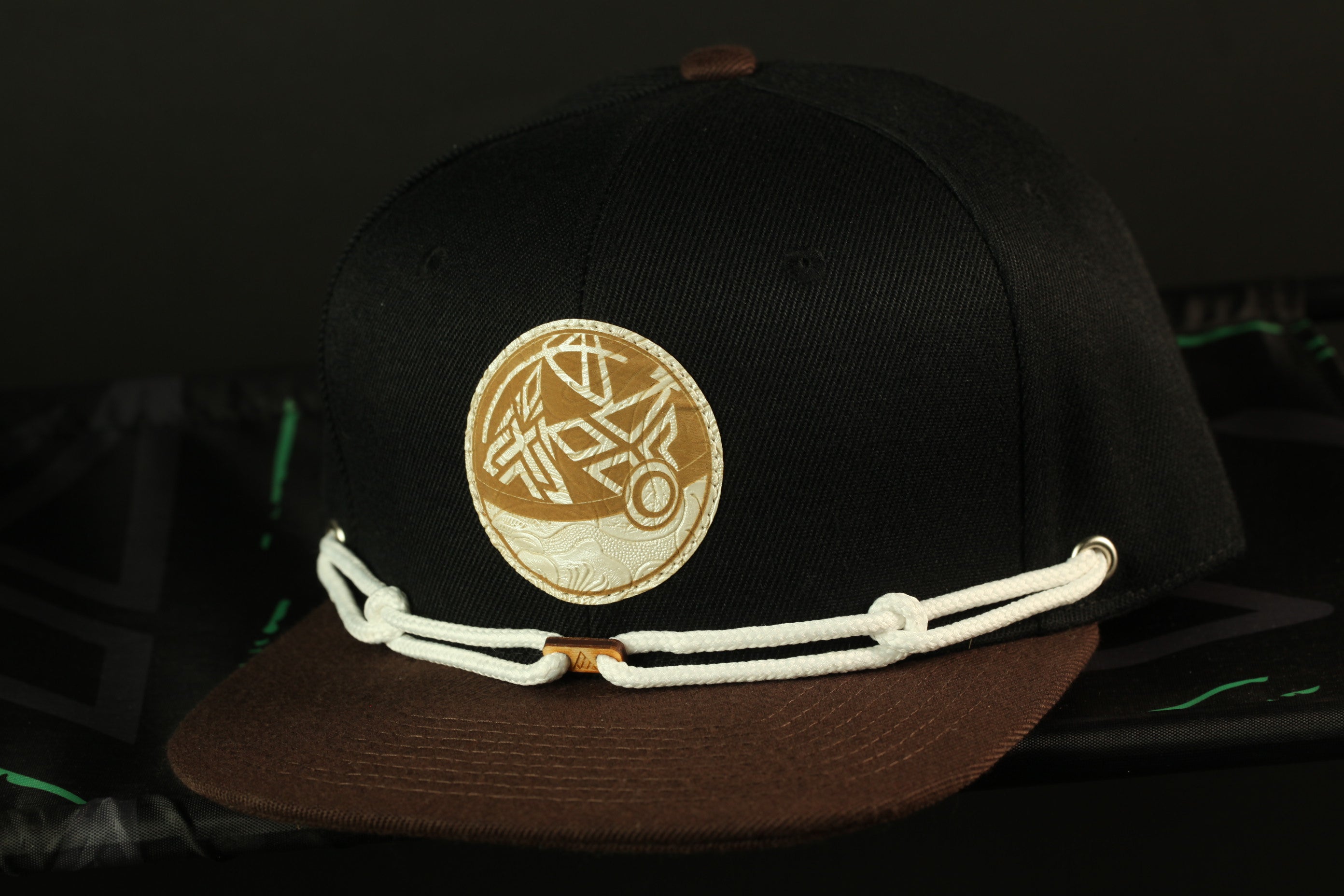 A black baseball cap with a gold circular logo on the front.