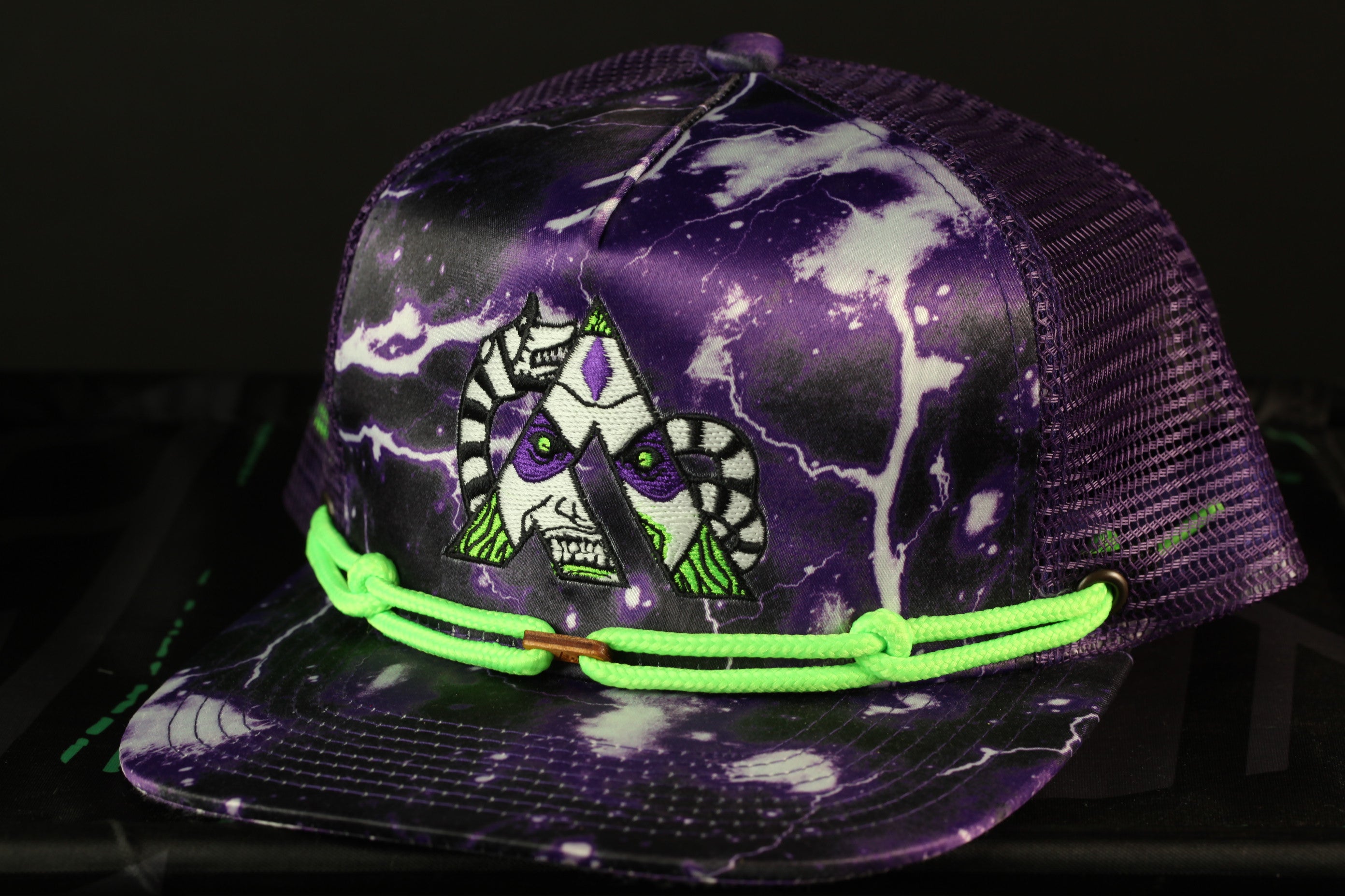 A purple baseball cap with a graphic design featuring a pair of cartoon-like faces on the front.