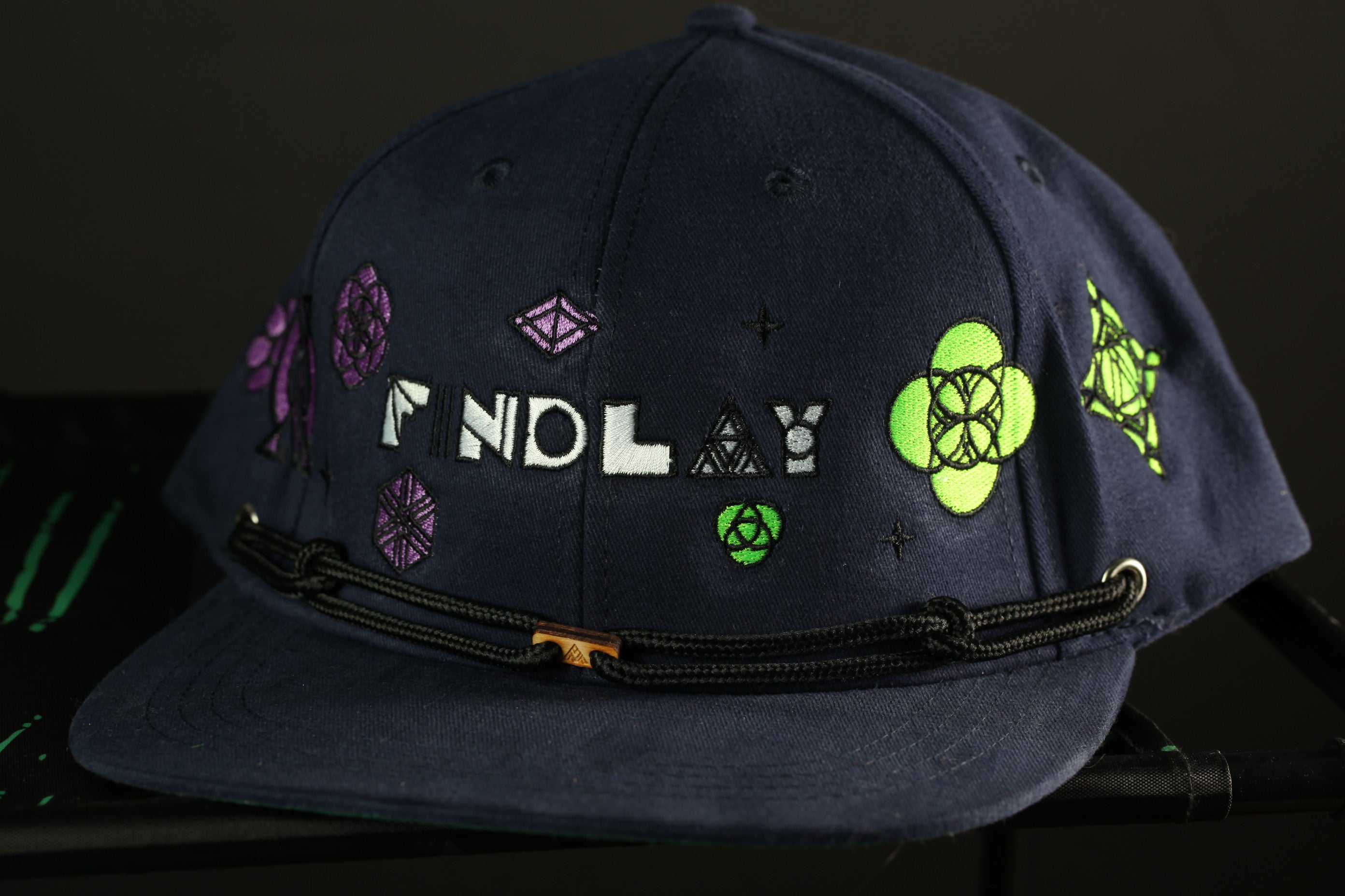A navy blue baseball cap with various colorful designs and text on it.