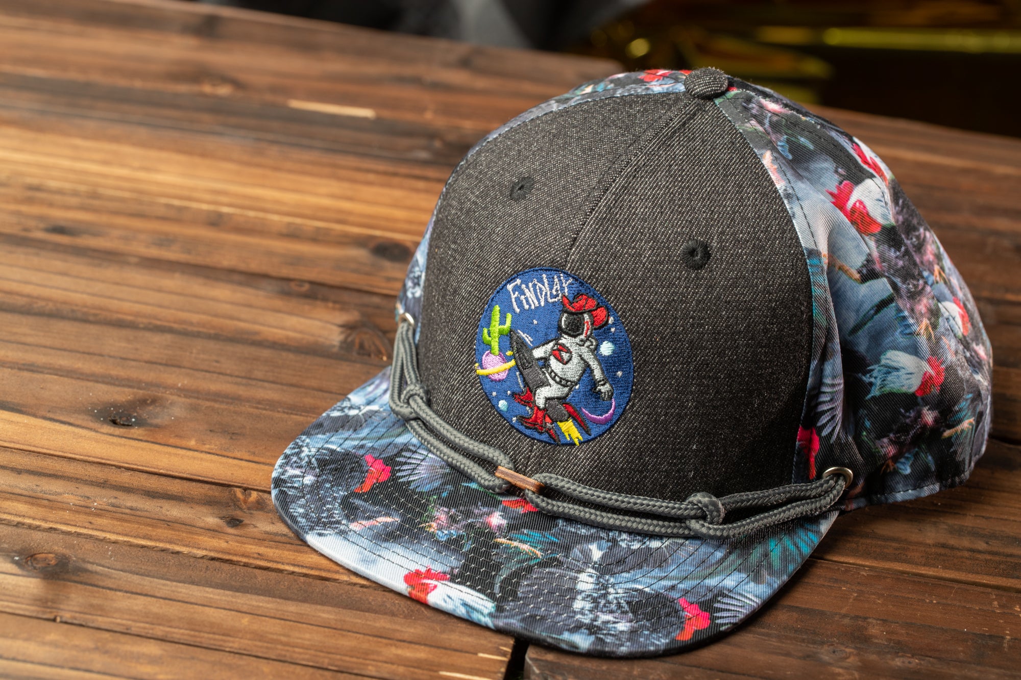 A gray baseball cap with a colorful, patterned design and a circular patch featuring a cartoon character.
