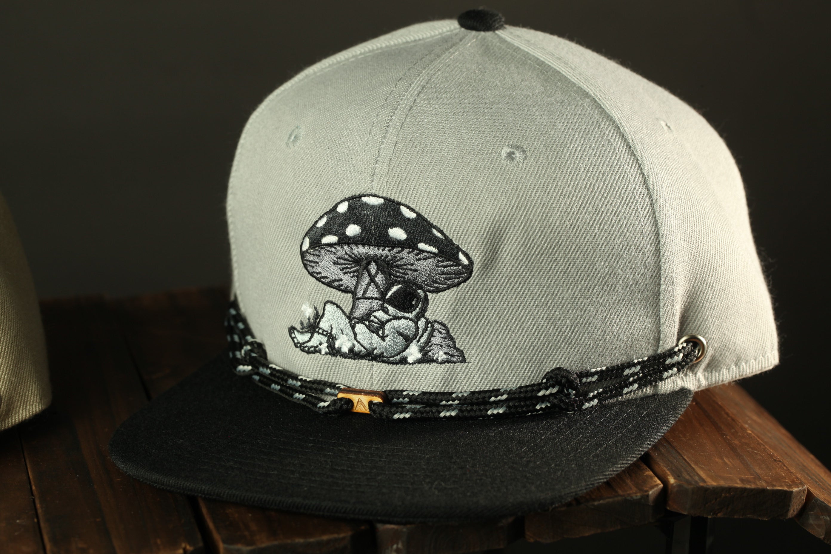 A gray baseball cap with a black and white mushroom design and a black strap.