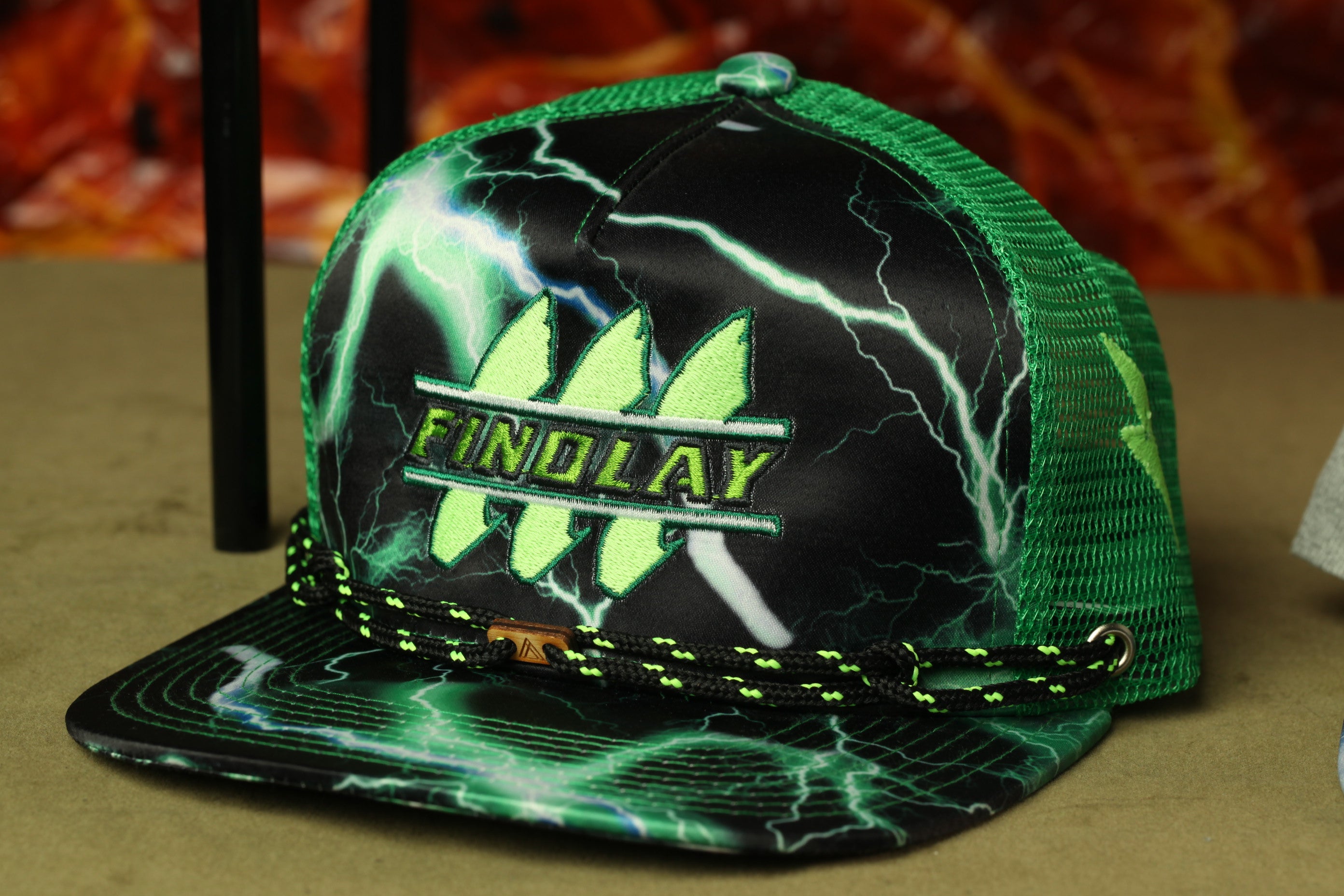 A green and black baseball cap with a lightning bolt design, featuring the word "FINOLAY" on the front.
