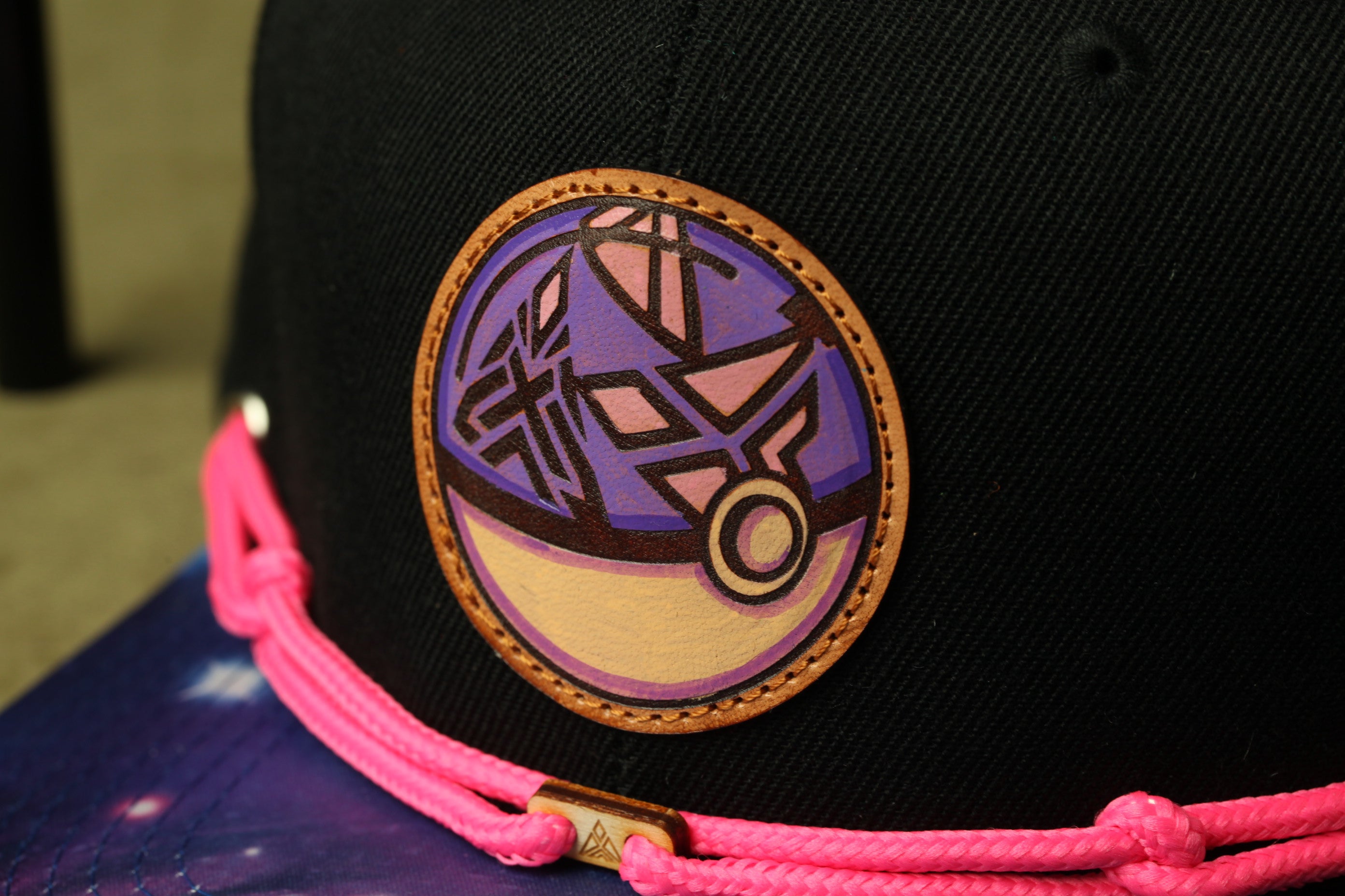 A close-up view of a black baseball cap with a colorful, abstract design on the front.