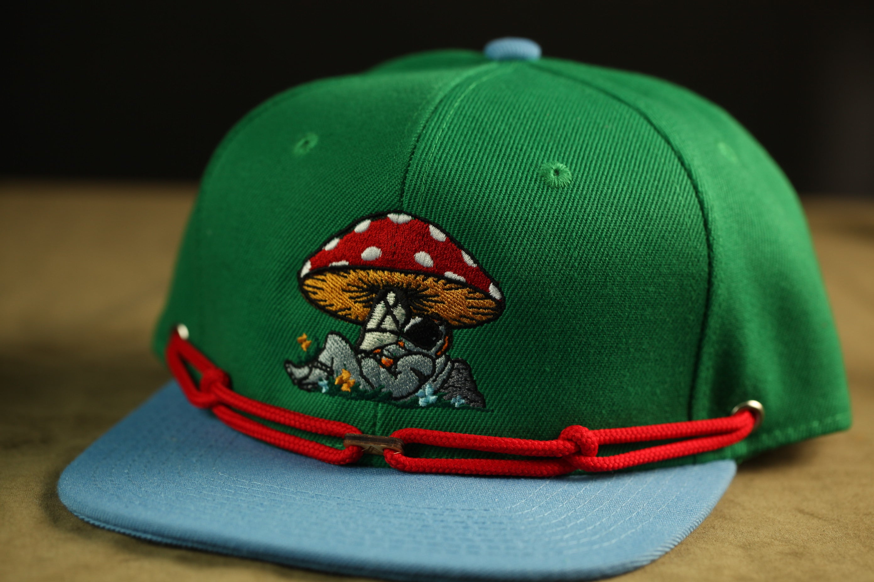 A green baseball cap with a red mushroom design and a blue brim.