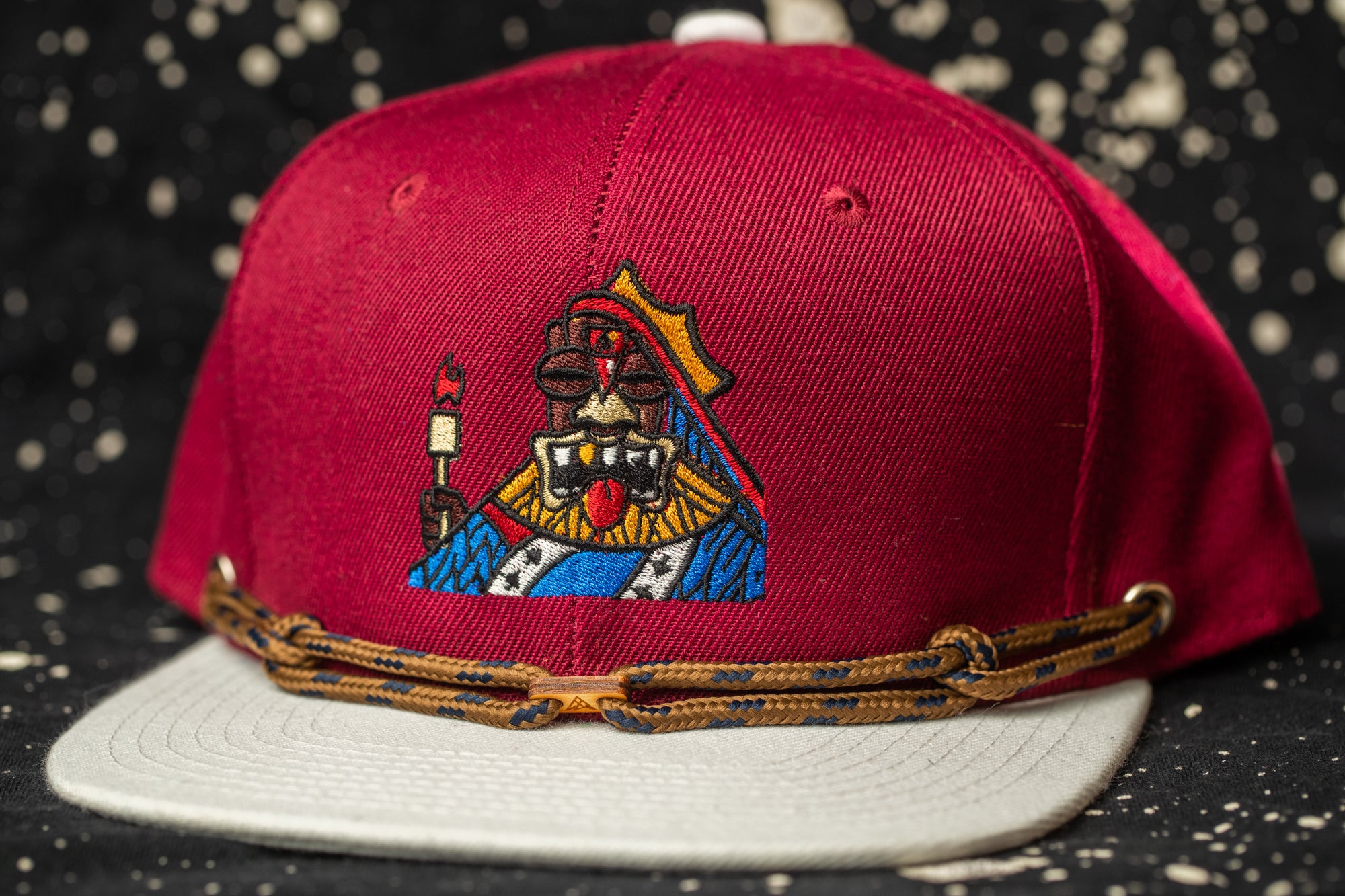 A red baseball cap with a colorful embroidered design on the front.