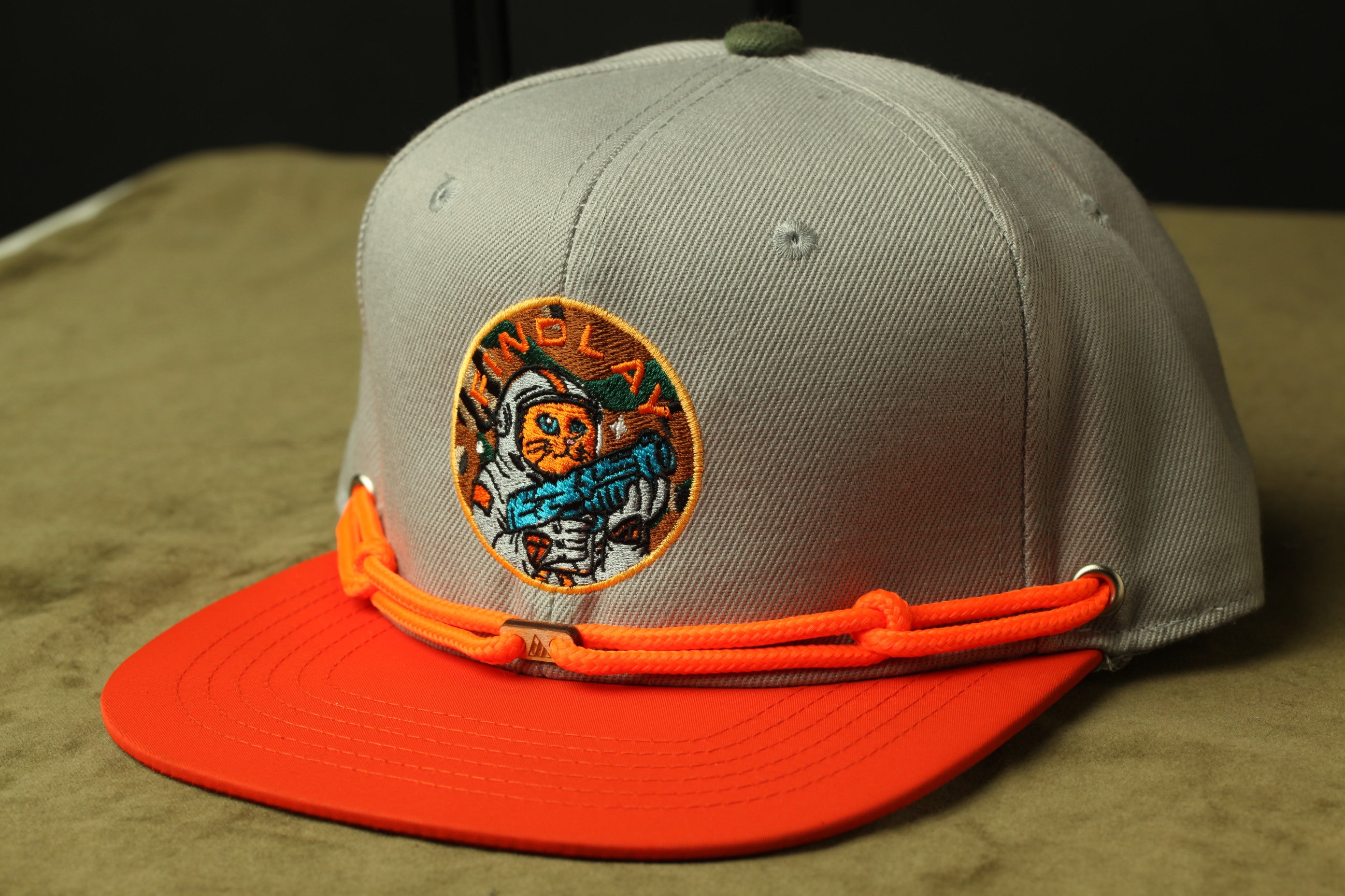 A gray baseball cap with an orange brim and a circular patch featuring a cat and the text "FINLAND" on it.