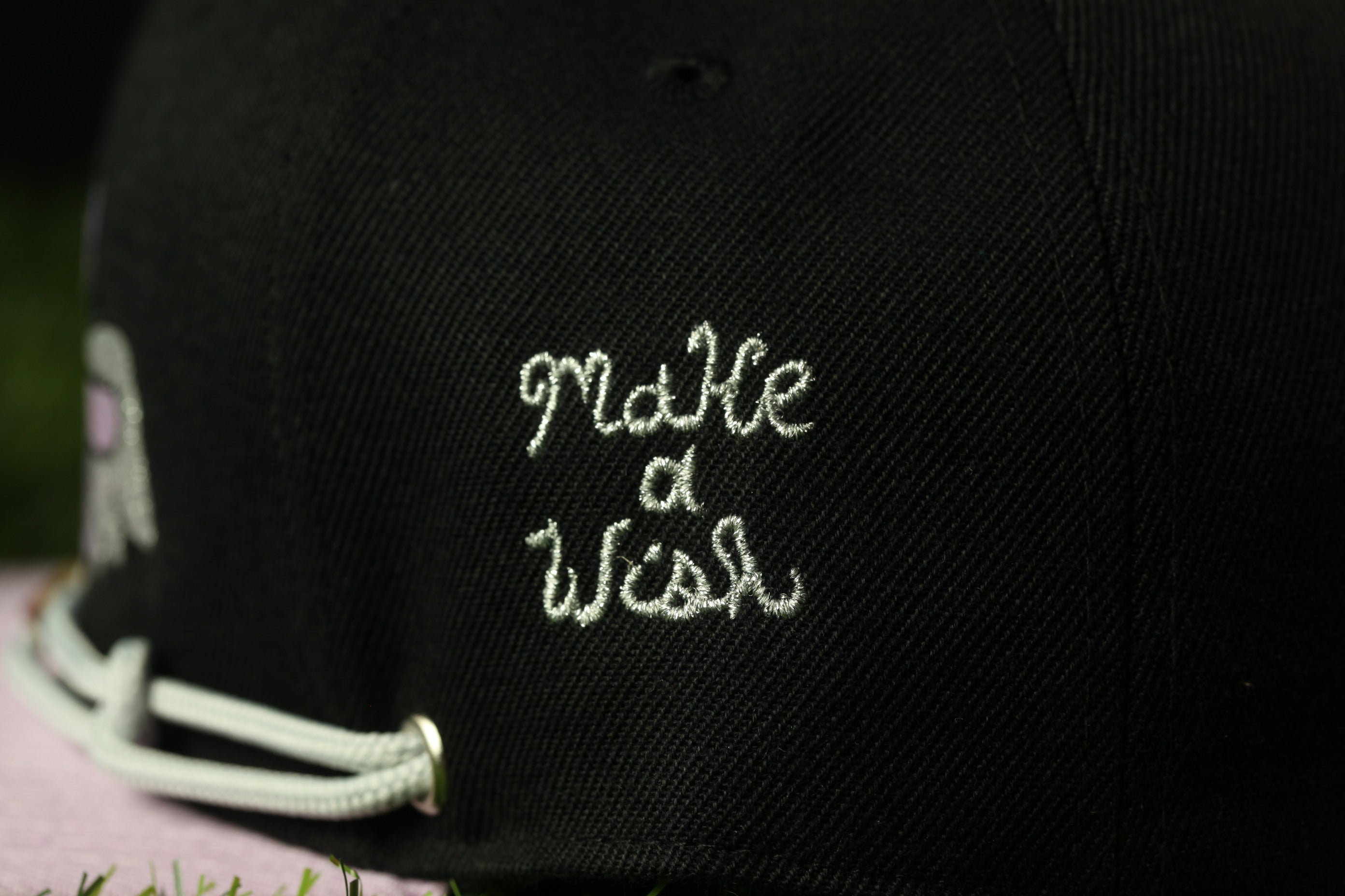 A close-up view of a black baseball cap with the embroidered text "Make a Wish" on the back.