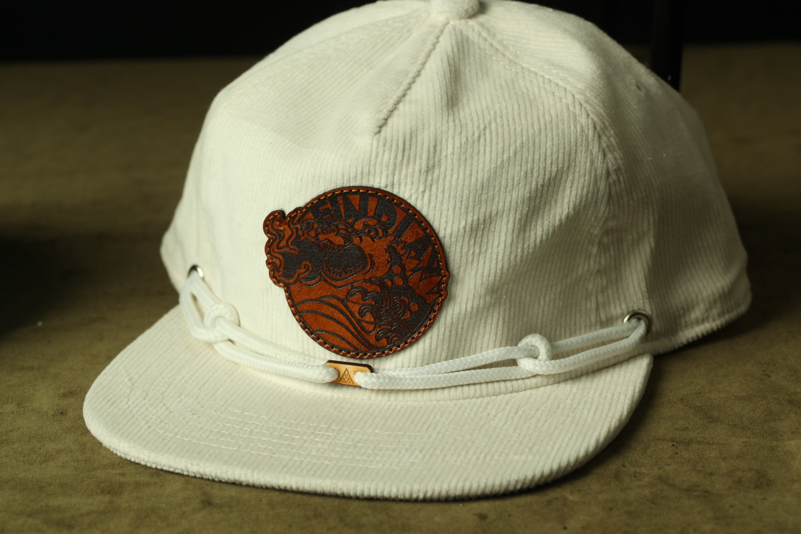 A white baseball cap with a brown leather patch on the front.