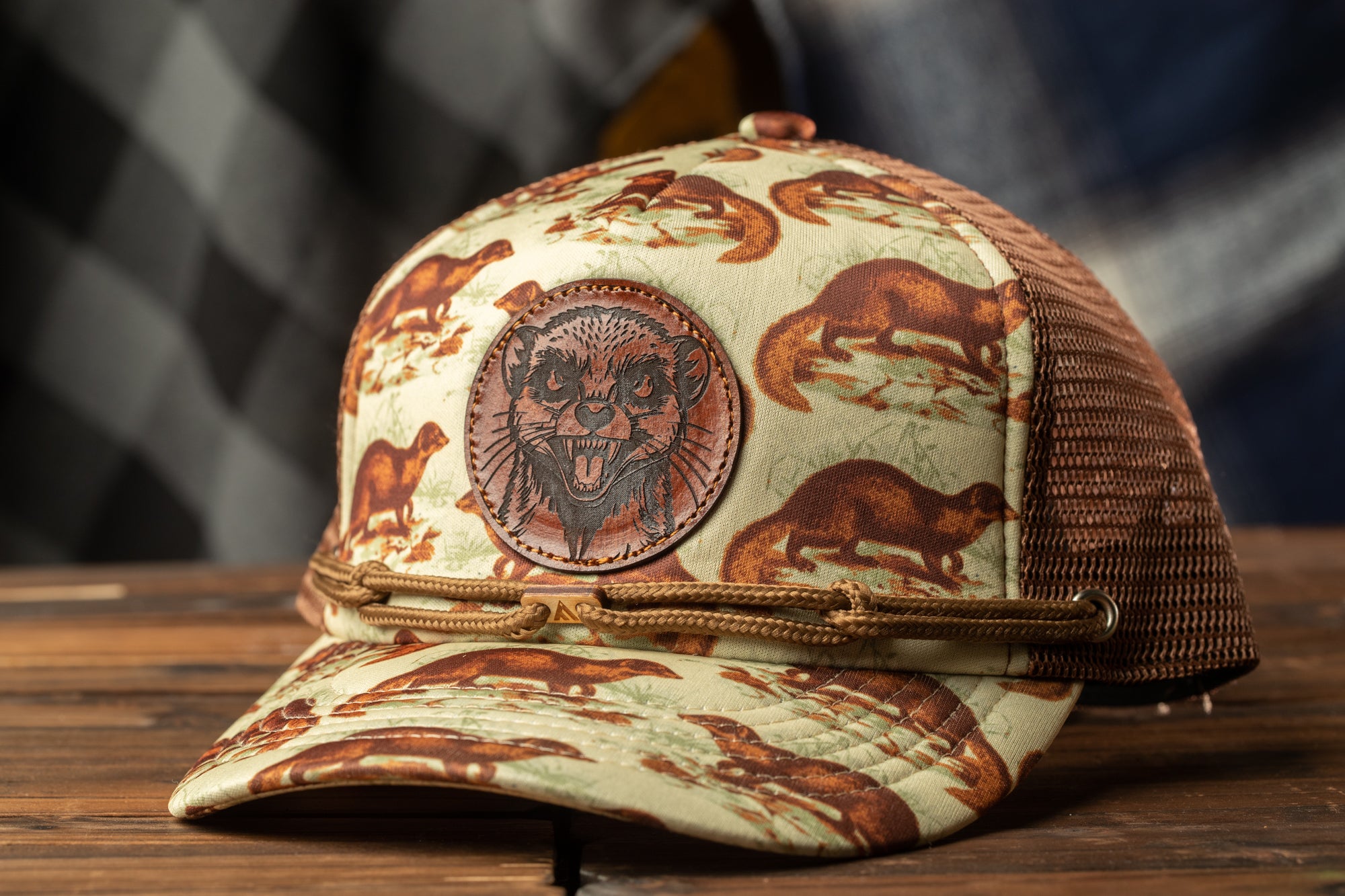 A beige baseball cap with a brown animal print pattern and a brown leather patch featuring a cartoon animal face.