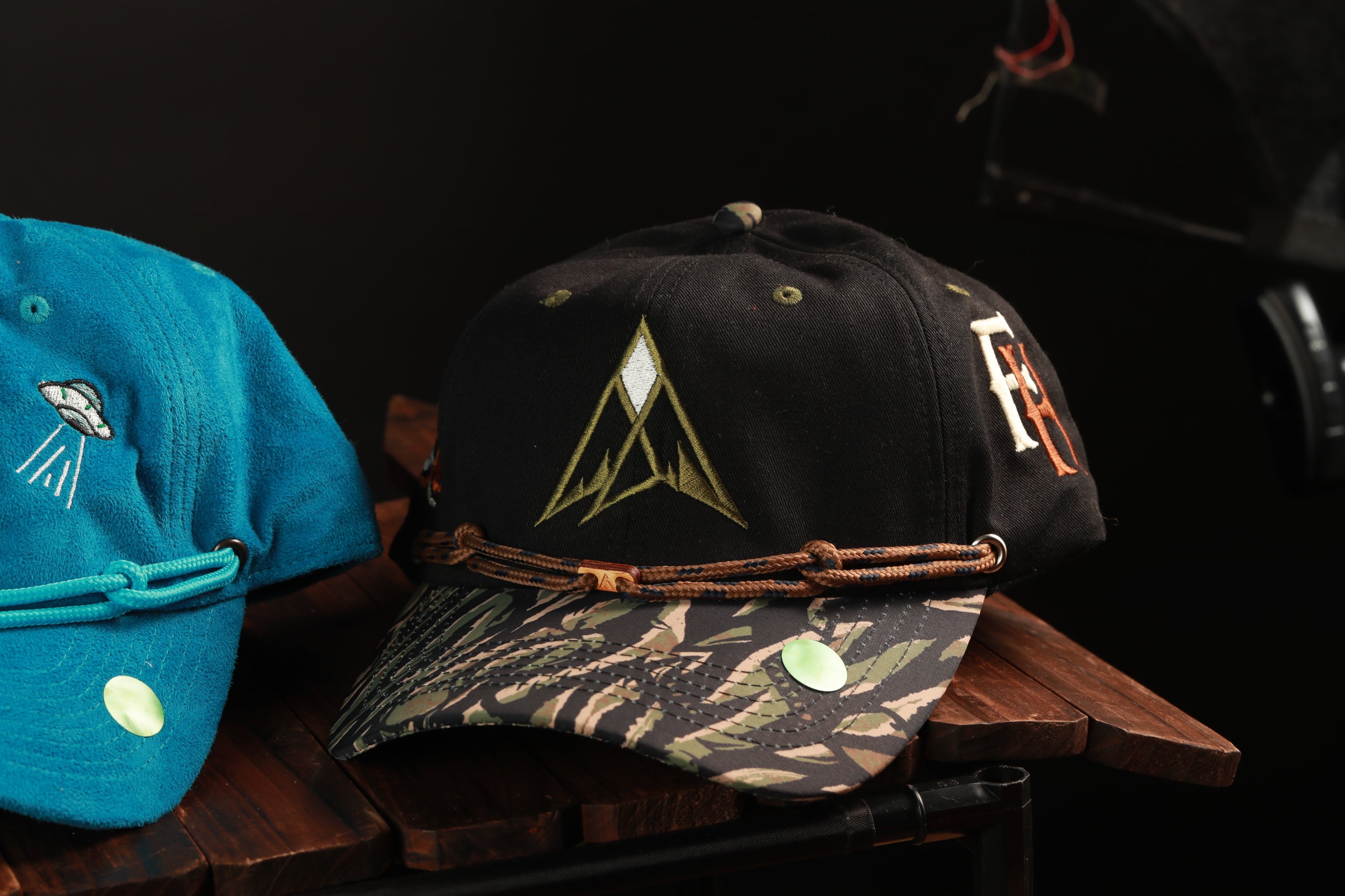 Two baseball caps are displayed on a wooden surface, one black and one blue.