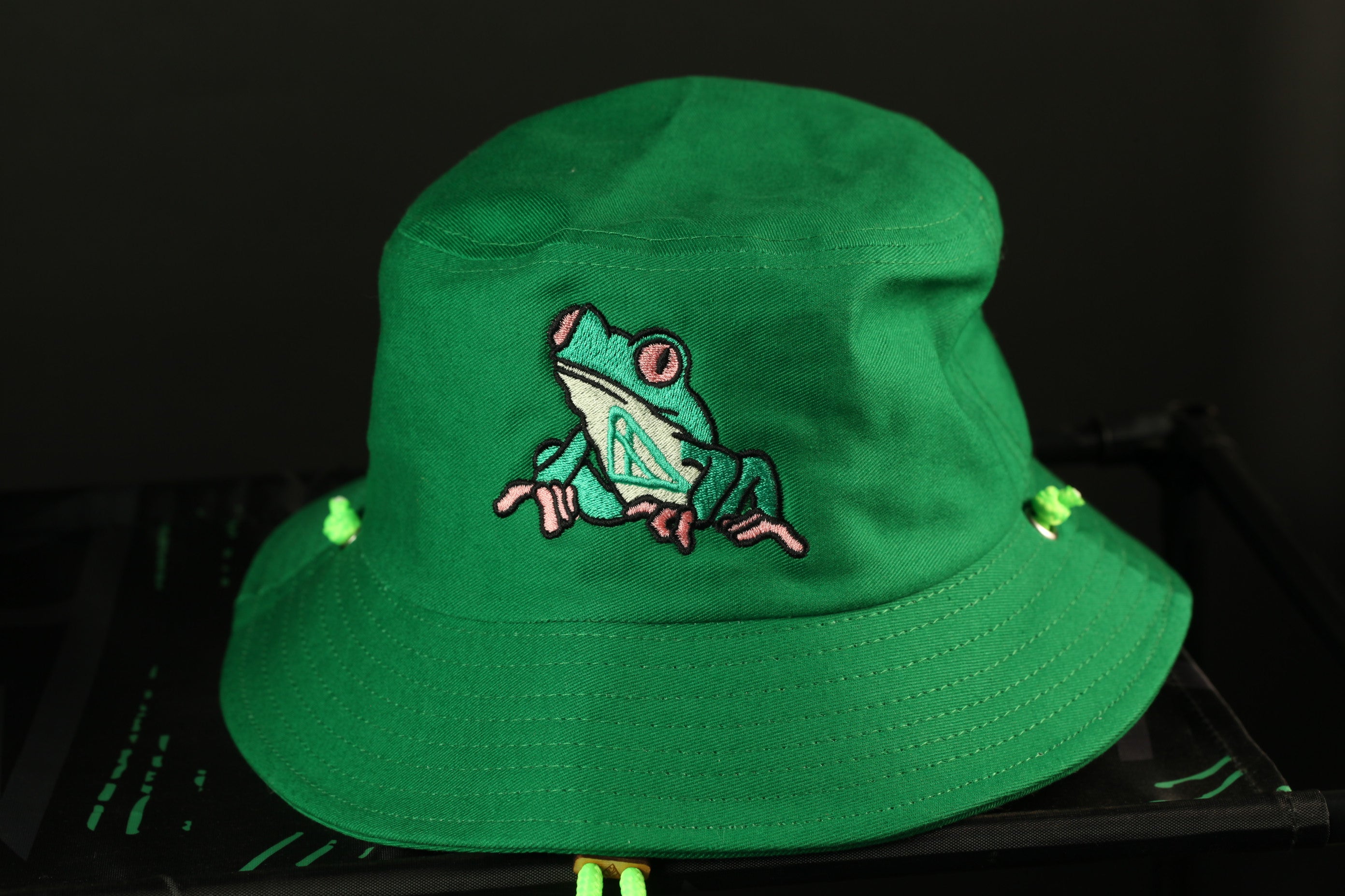 A green bucket hat with a frog embroidered on it.