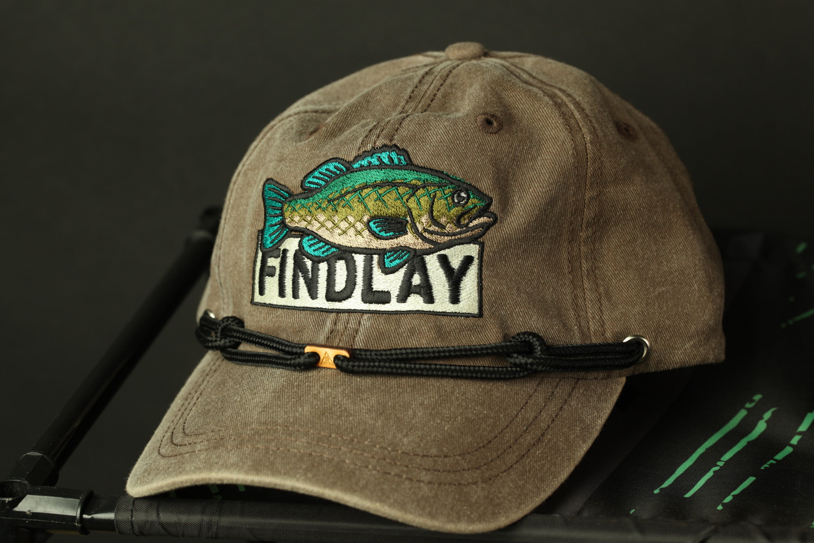 A tan baseball cap with a fish embroidered on it, featuring the word "FINDlay" on the front.