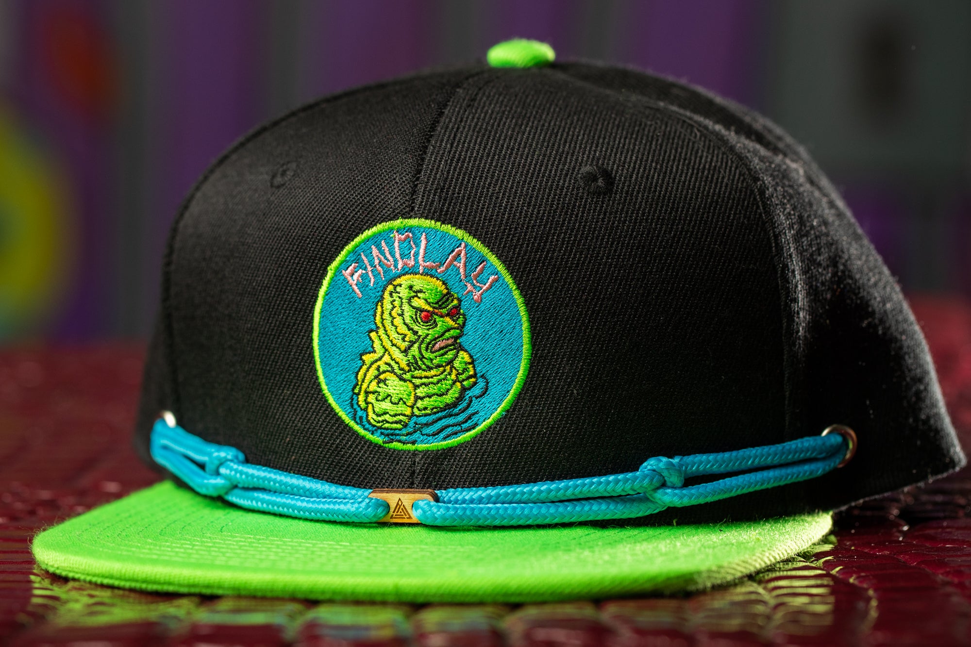 a black hat with a green brim and a blue band around the brim