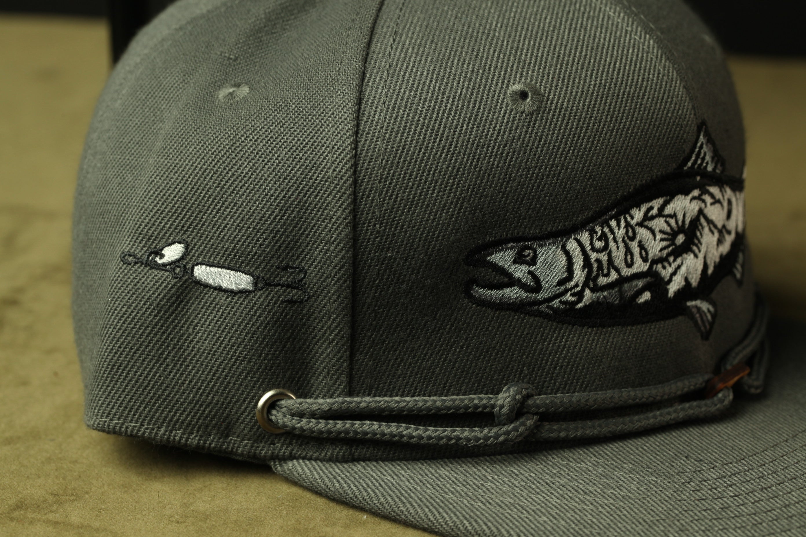A gray baseball cap with a fish embroidered on it.