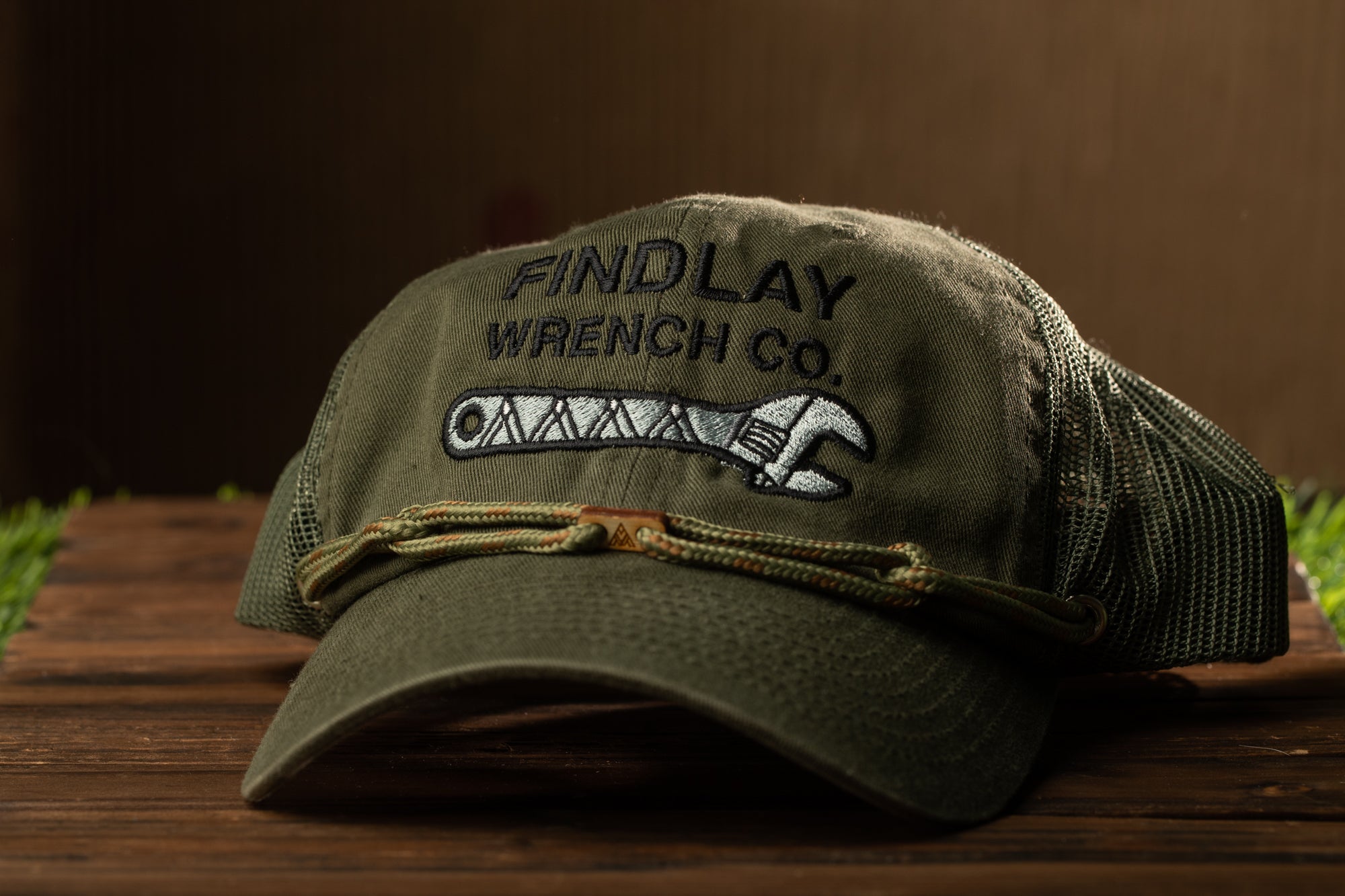 A green baseball cap with the text "FIND LAY" and "WRENCH CO." printed on it, along with a wrench embroidered on the front.