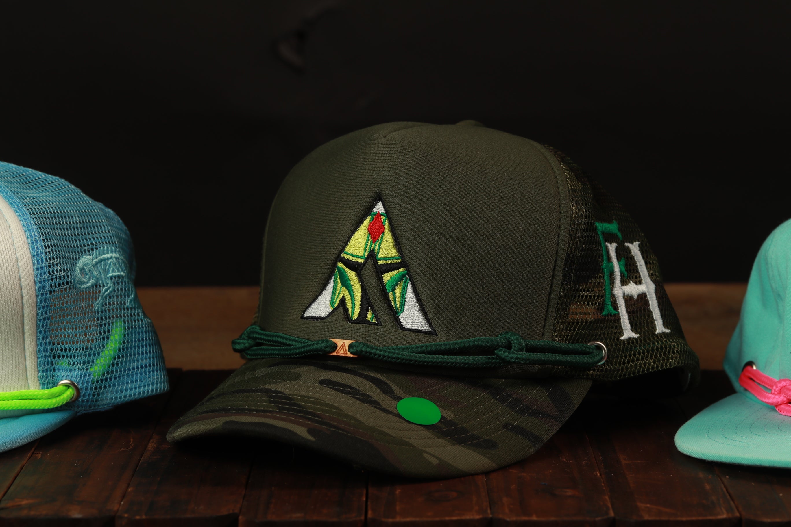 A collection of three baseball caps, each with unique designs and colors, displayed on a wooden surface.