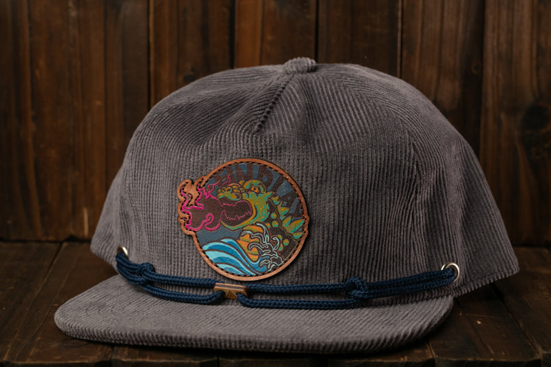 A gray baseball cap with a circular patch featuring a colorful design, placed on a wooden surface.