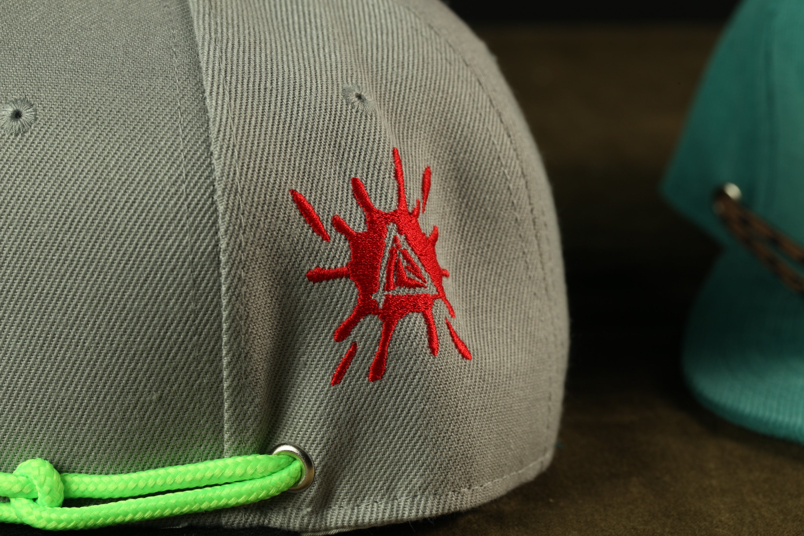 a close-up view of a gray baseball cap with a red embroidered logo on the side.