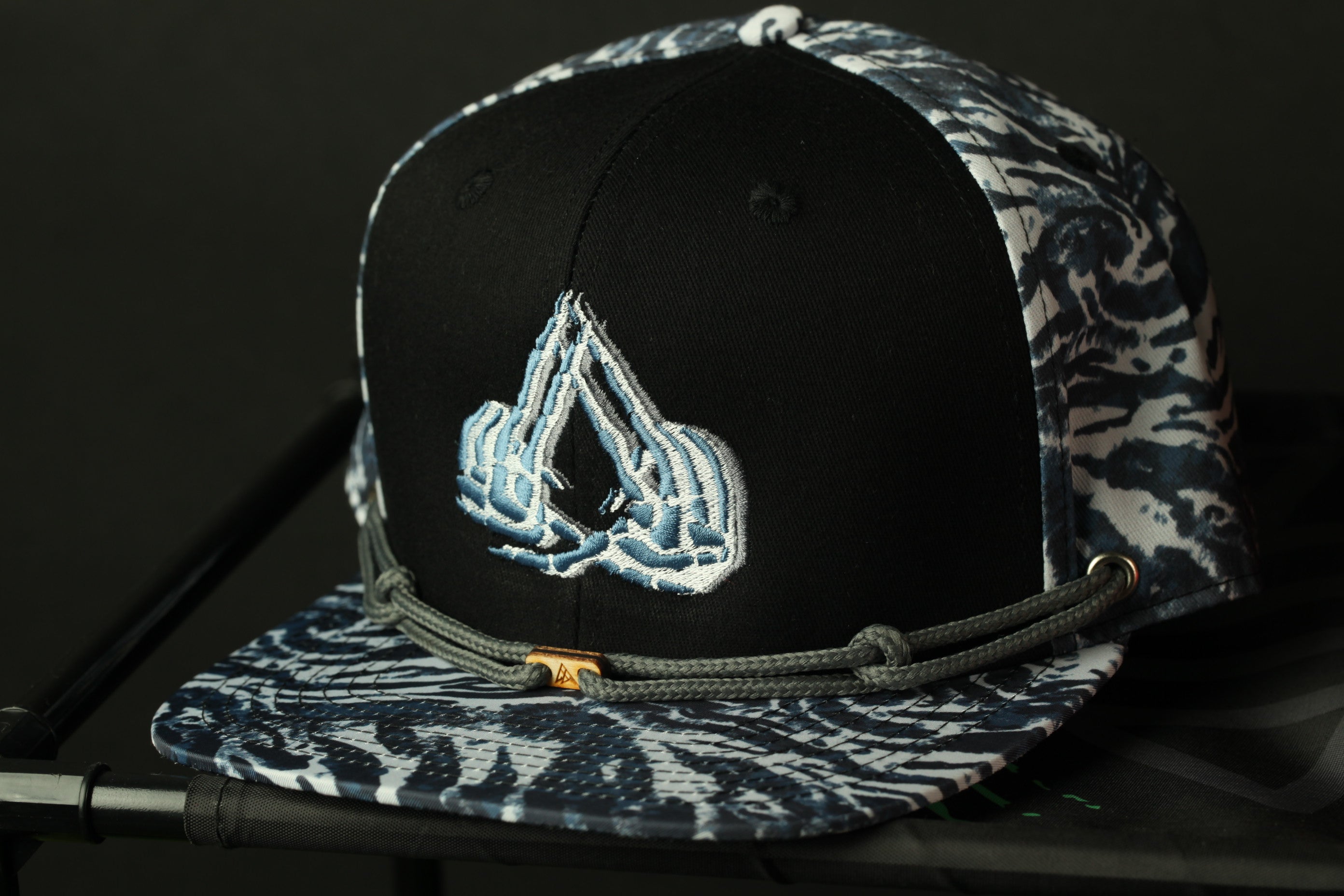 A black and white baseball cap with a unique embroidered logo on the front.
