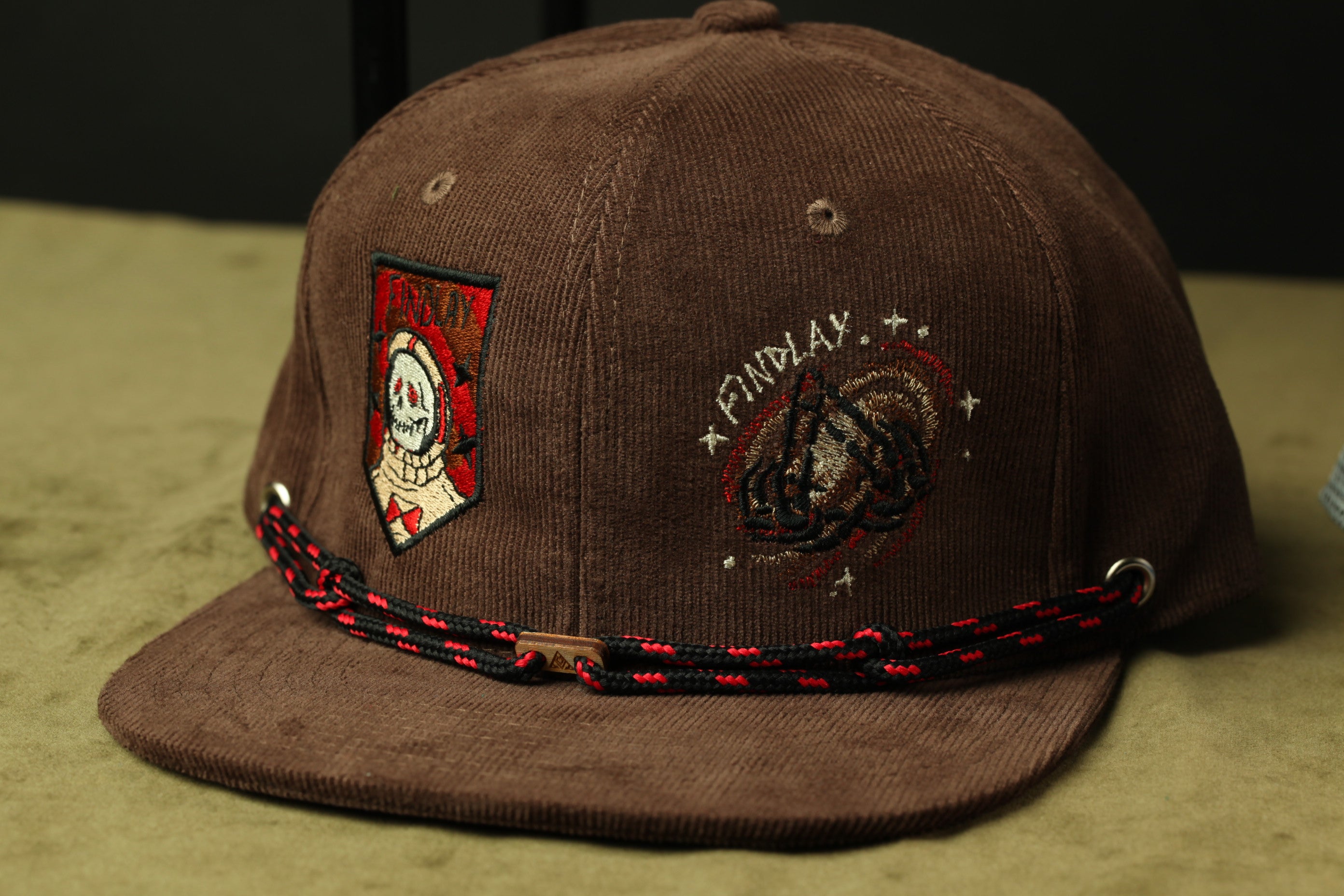 A brown baseball cap with various patches and embroidered designs on it.