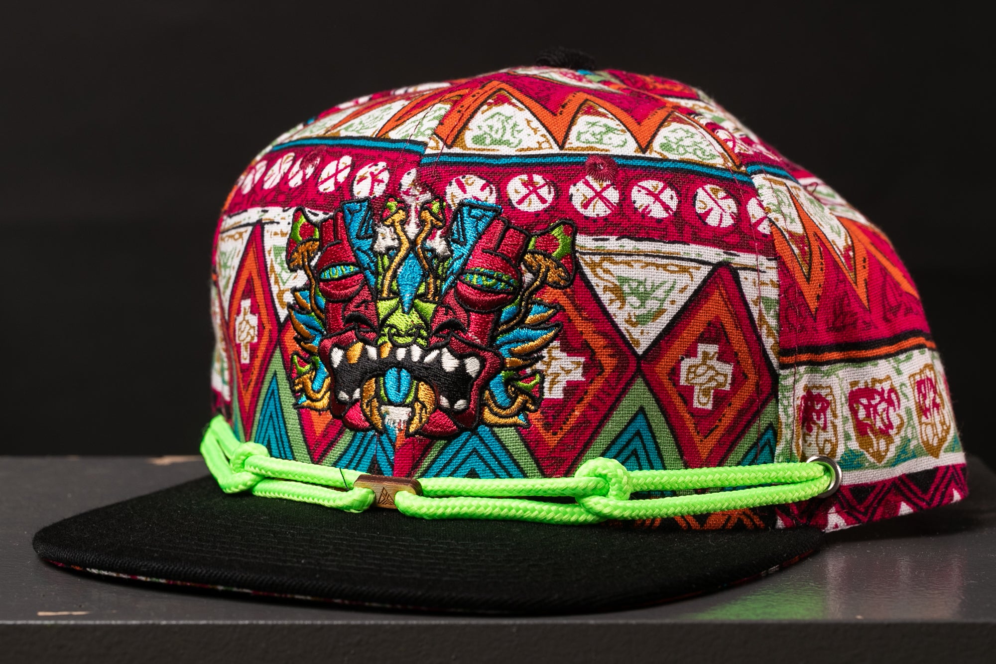 A colorful, patterned baseball cap with a dragon design on the front.