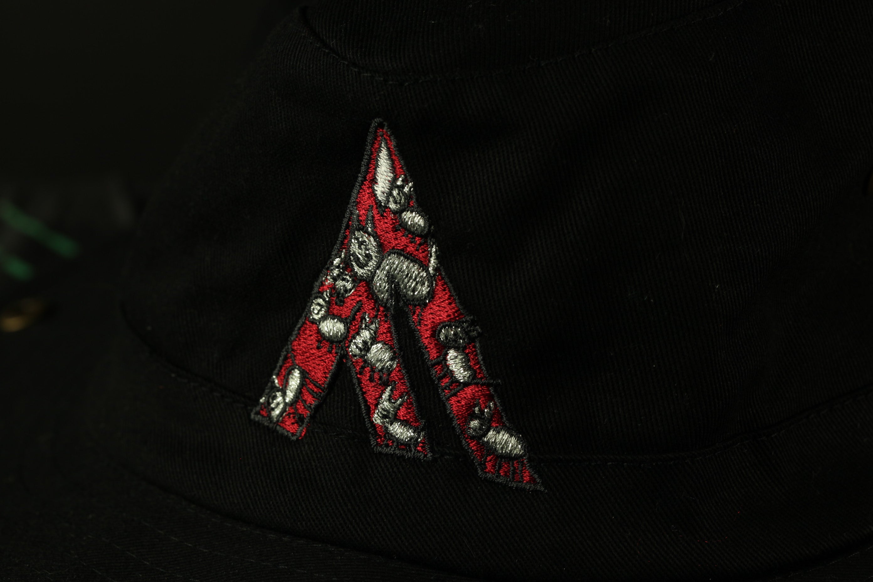 a close-up view of a black fabric with a red and silver embroidered letter 'A' on it.