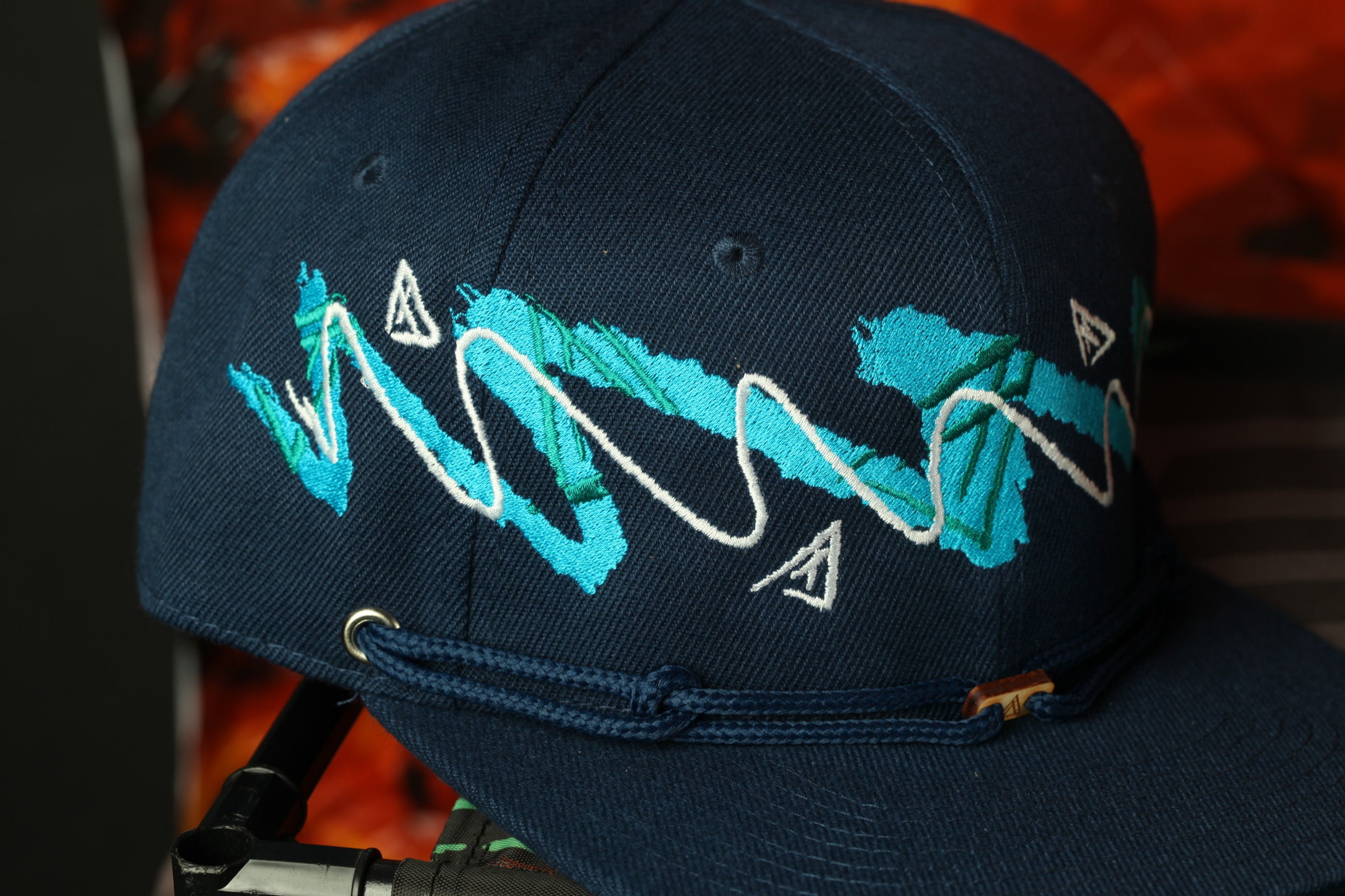 A close-up view of a navy blue baseball cap with a unique blue and white embroidered design.