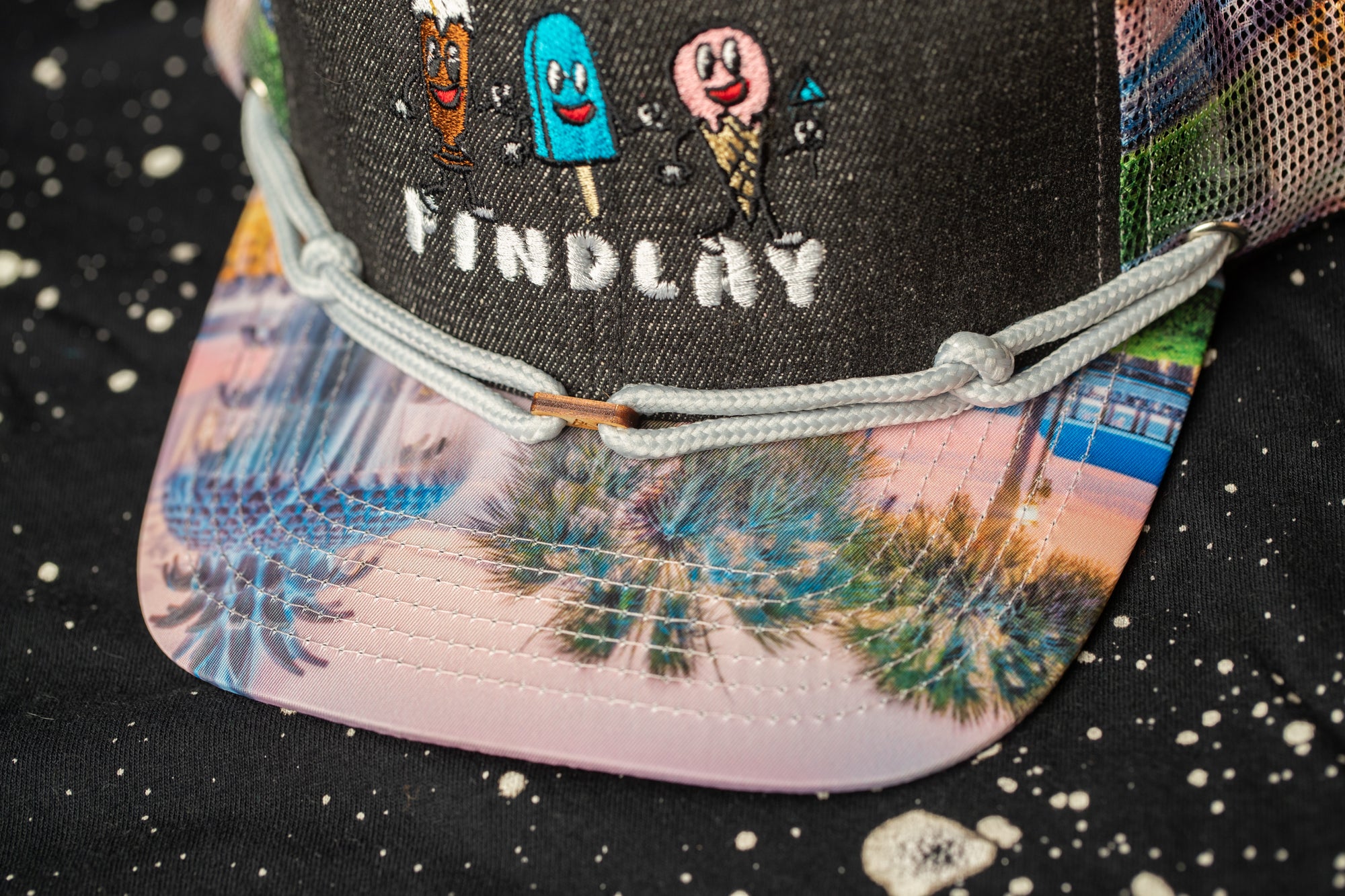 A close-up view of a colorful, patterned baseball cap with a cartoon ice cream cone design.
