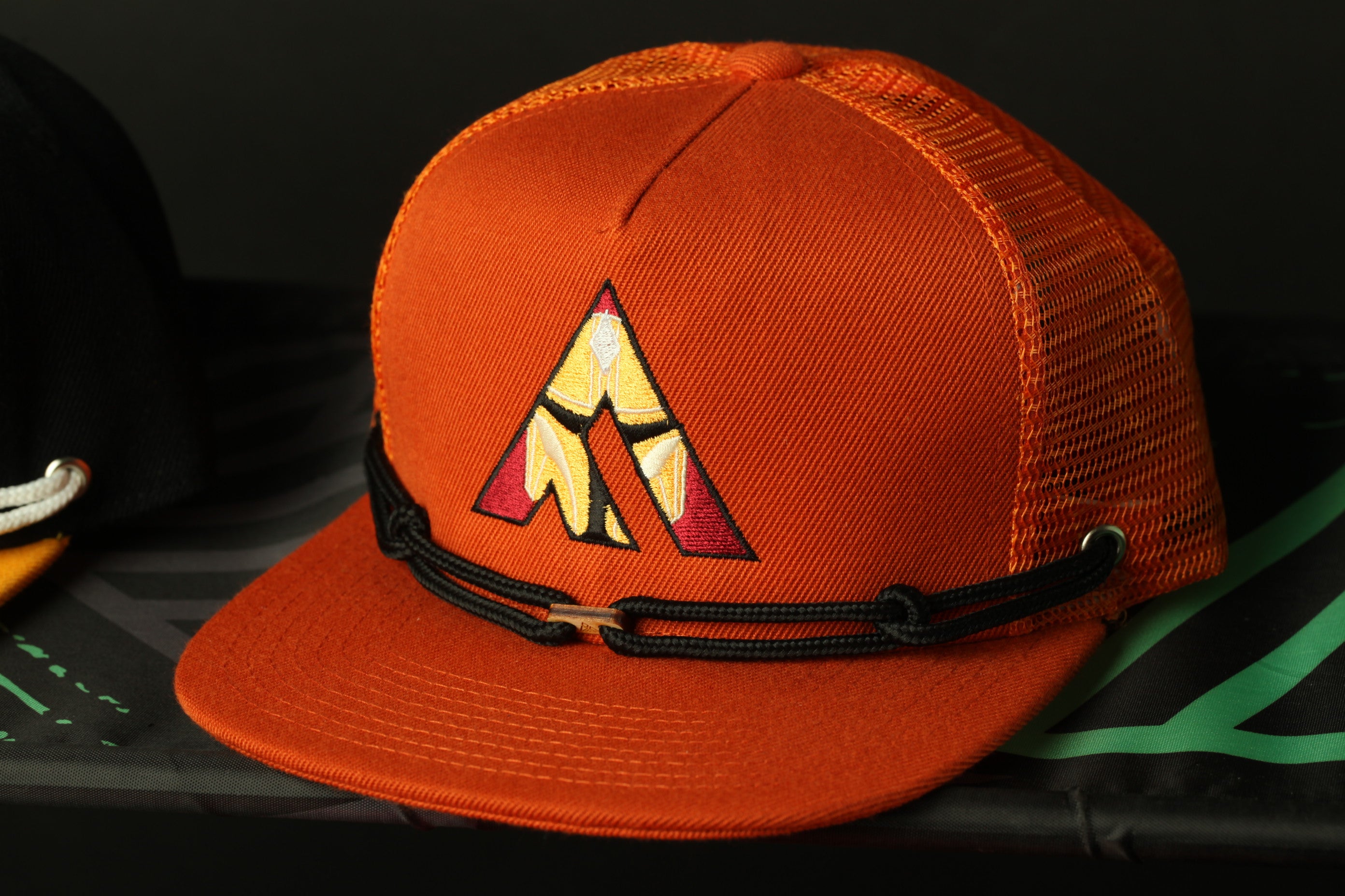 An orange baseball cap with a mesh back and a black adjustable strap.