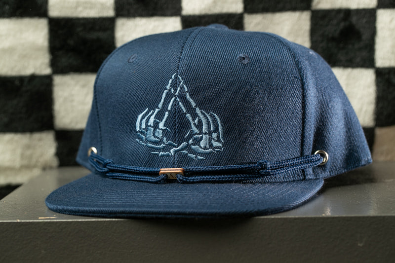 A navy blue baseball cap with a unique skull-like embroidered design on the front.