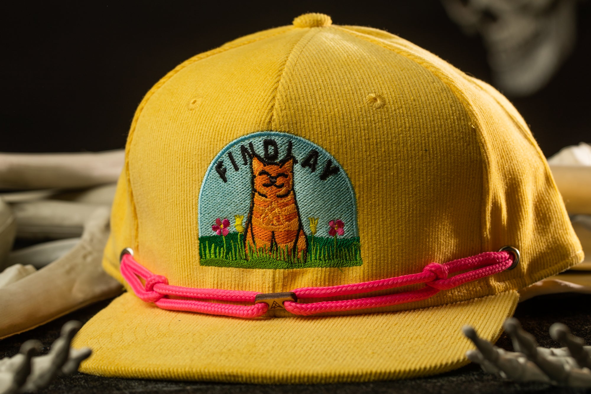 A yellow baseball cap with a cat embroidered on it, featuring the word "FINDAY" on the front.