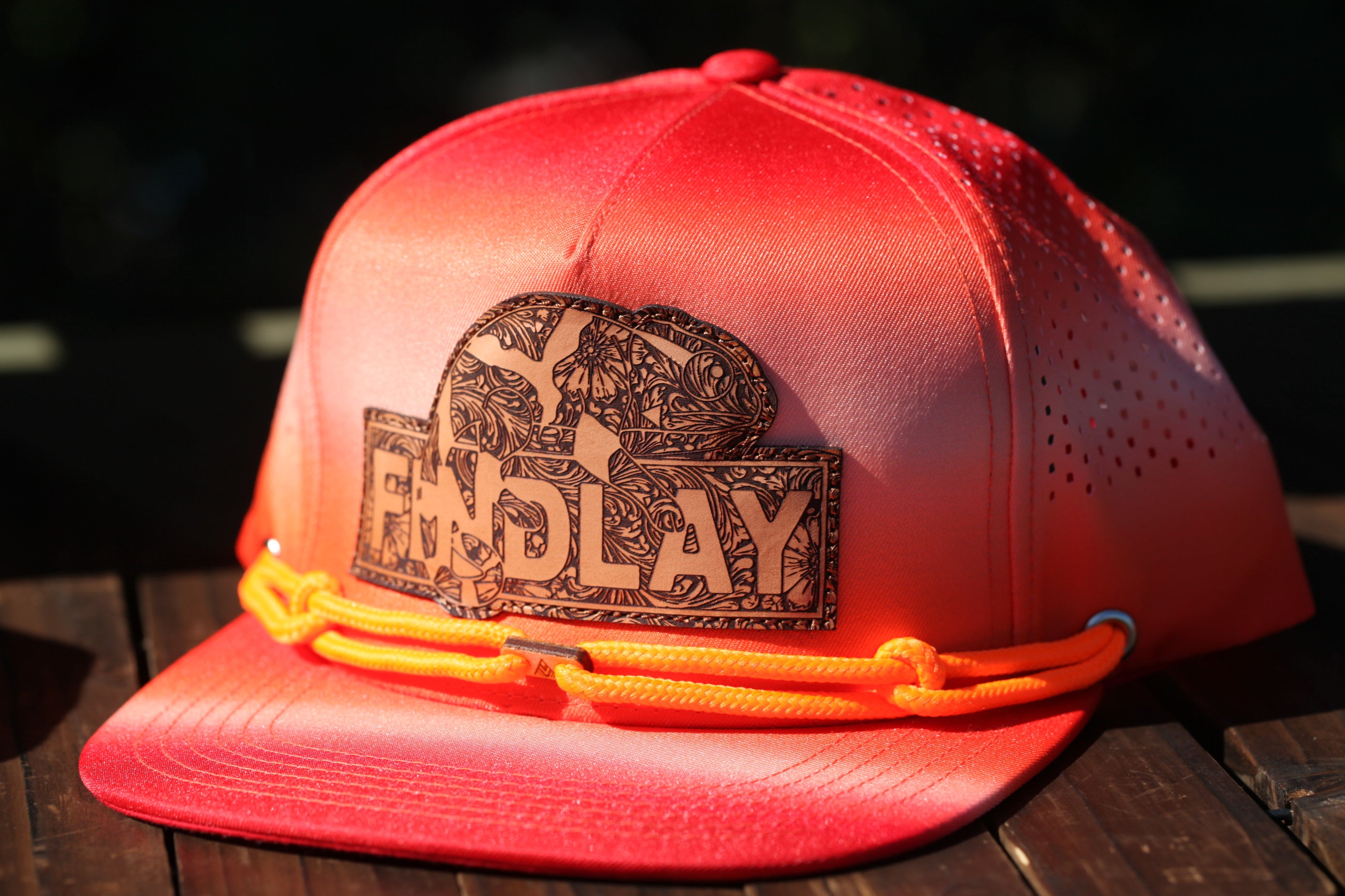 A red baseball cap with a printed logo on the front, sitting on a wooden surface.