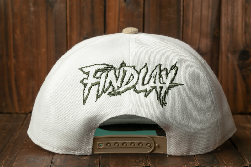 A white baseball cap with the word "FINDlay" embroidered on it, sitting on a wooden surface.