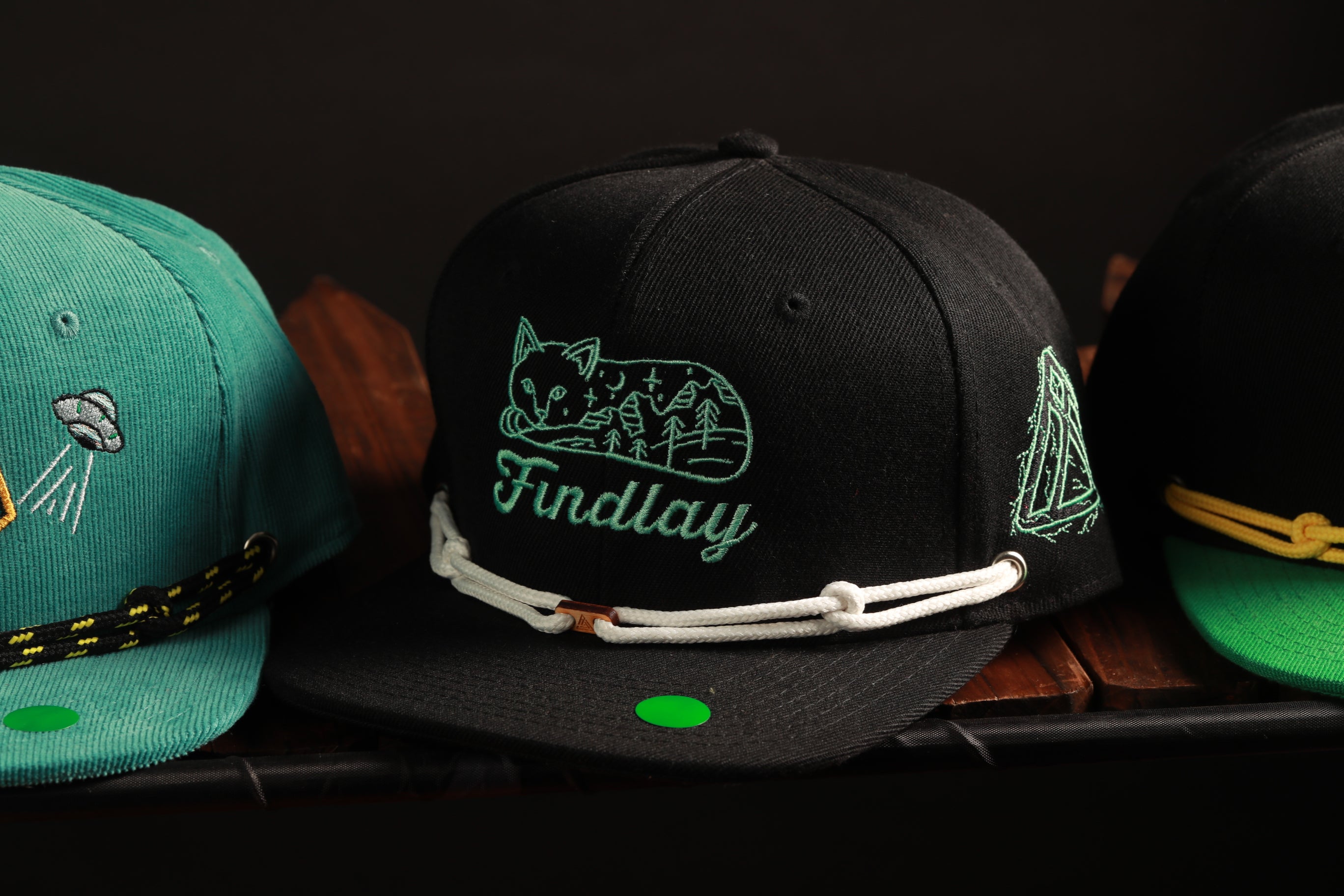 A collection of three baseball caps, each with unique designs and colors, displayed on a shelf.