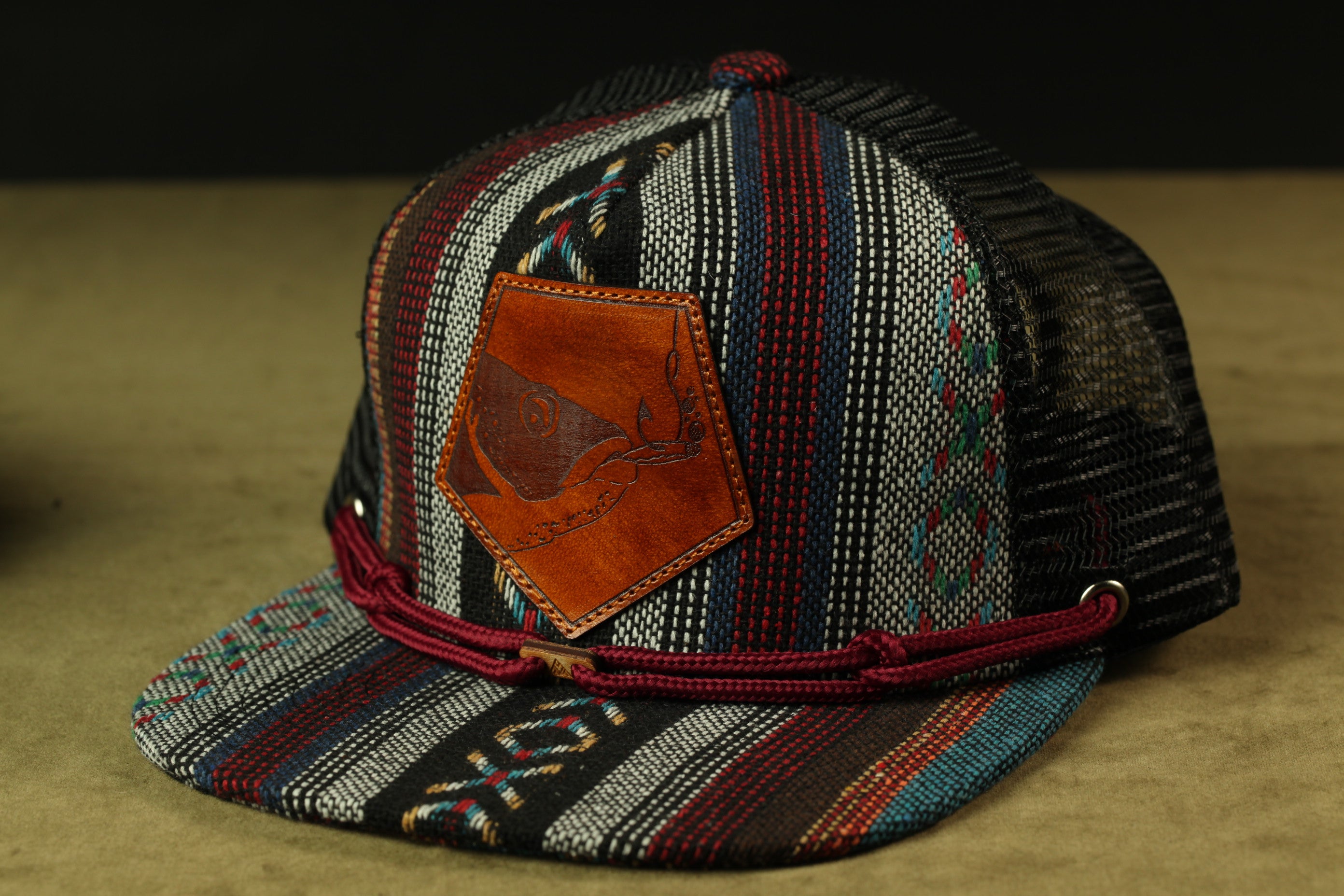 A colorful, patterned baseball cap with a leather patch on the front.