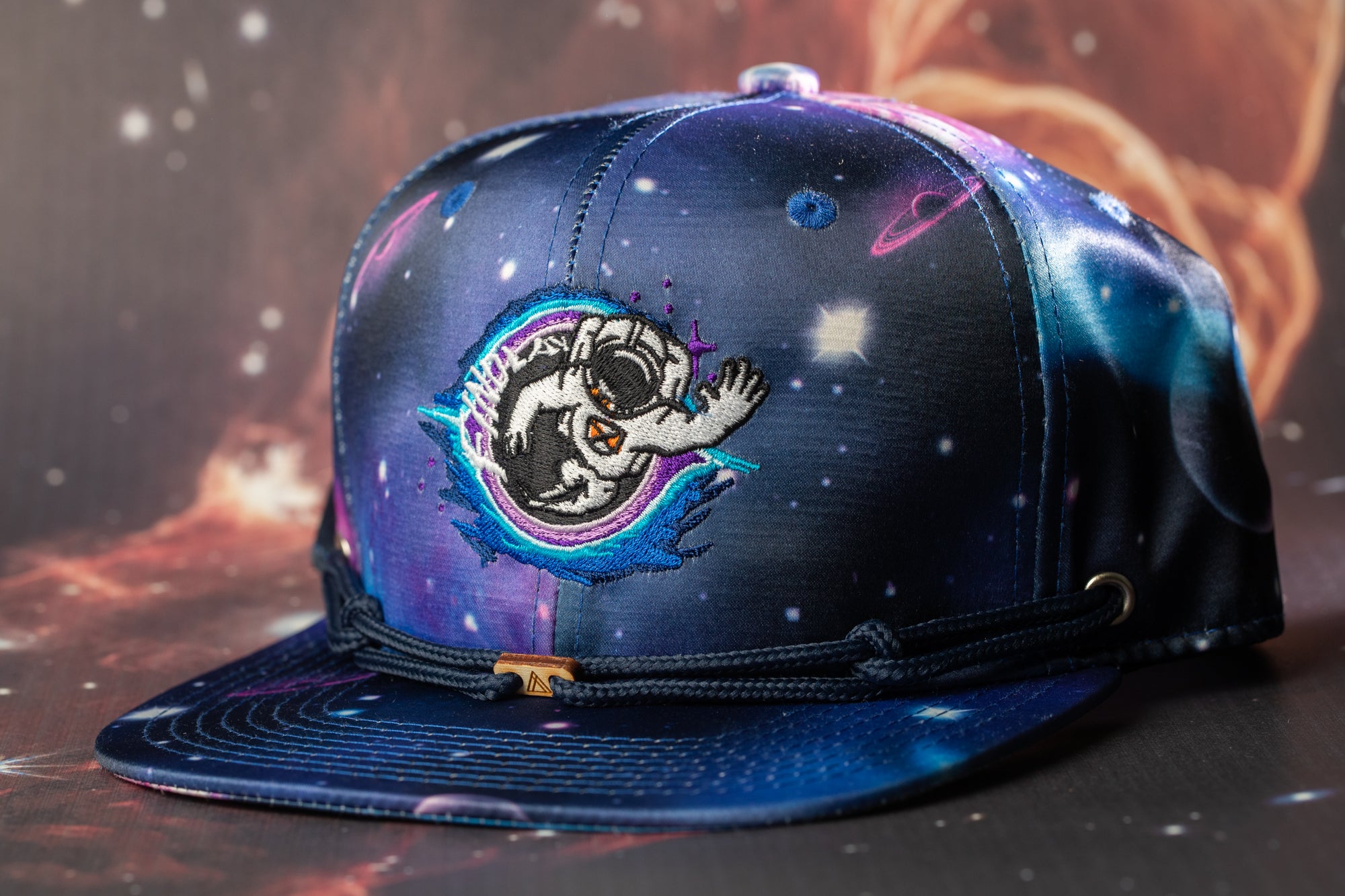A colorful baseball cap with a space-themed design, featuring a space suit and planets.