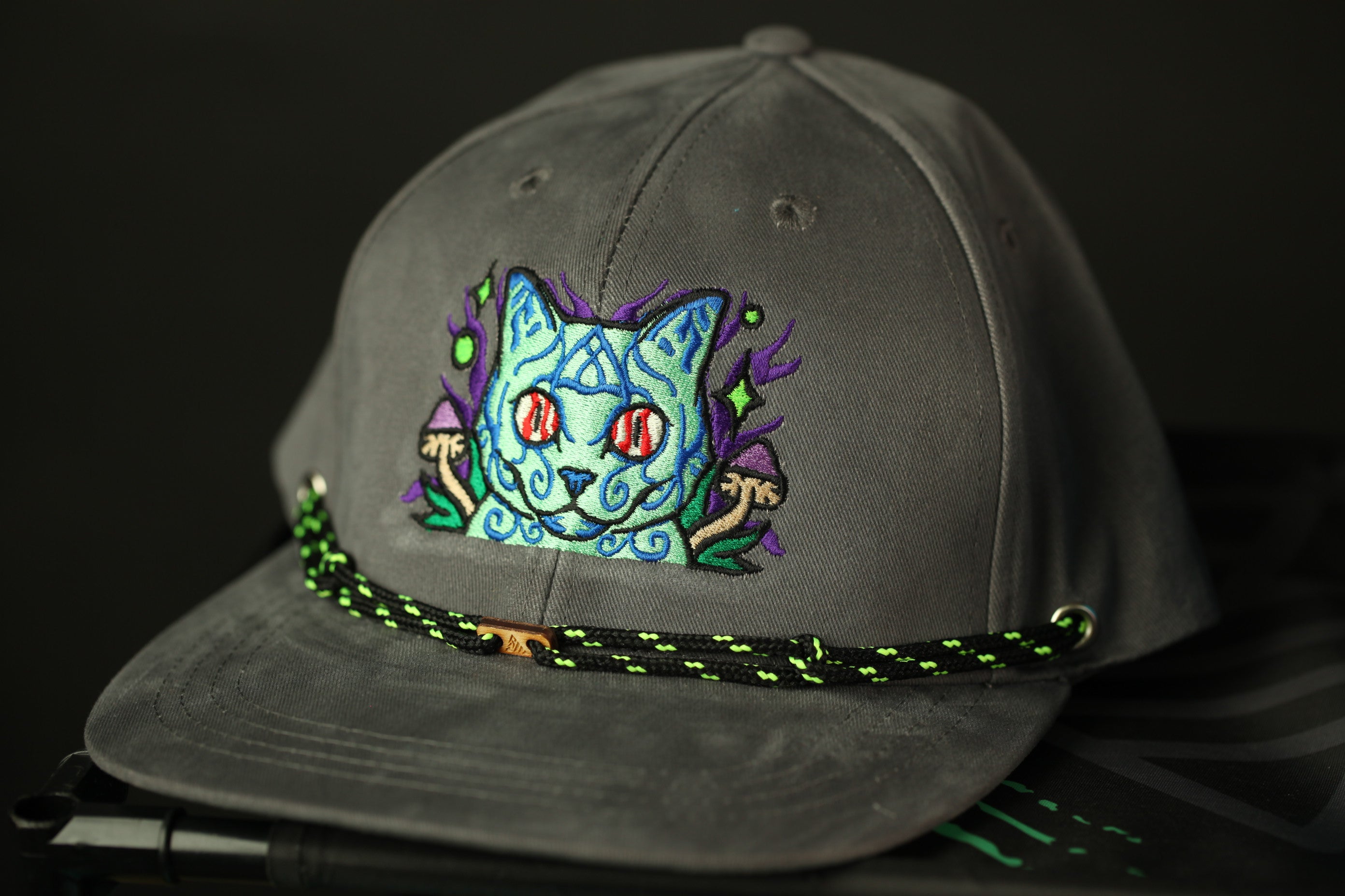 A gray baseball cap with a colorful, cartoonish cat embroidered on the front.